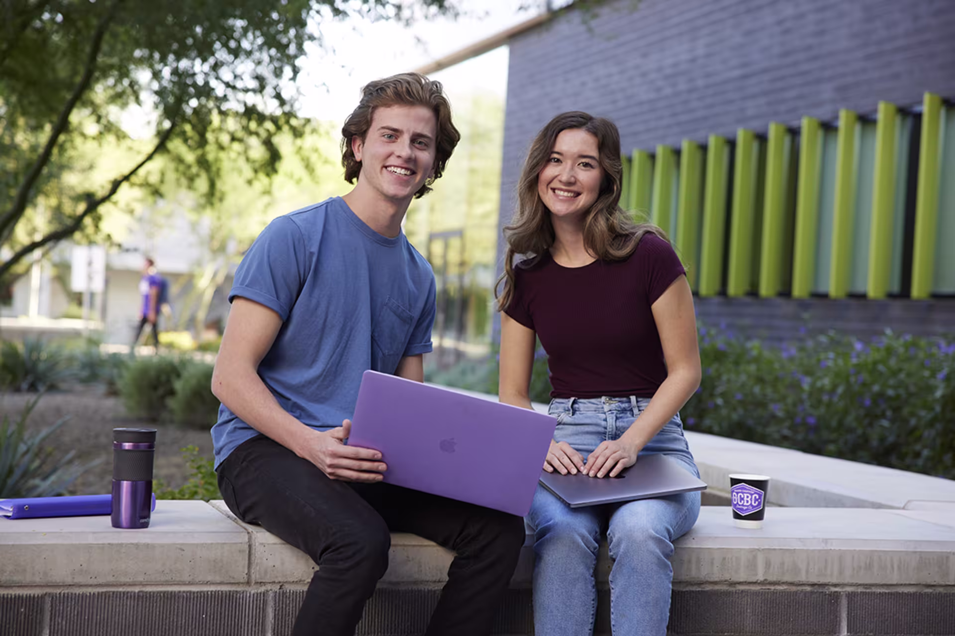 Two GCU research students sitting outside a building looking at a laptop.
