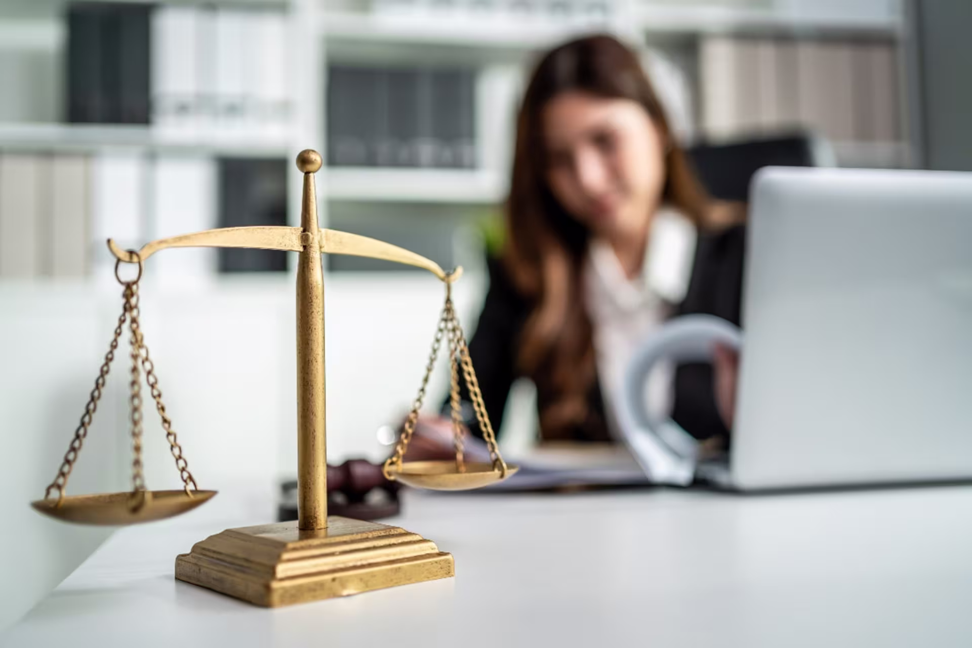 Close-up of a government employee on working table in an office with the hammer and equality scales of justice in the foreground.