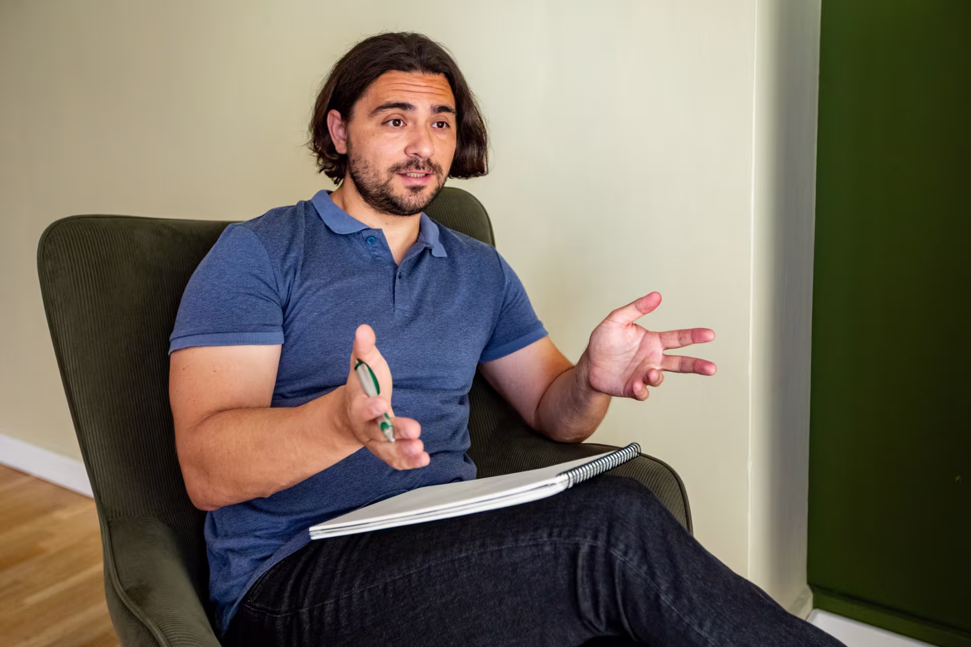 Pleasant male mental health professional sitting in armchair in office and talking during therapy session.
