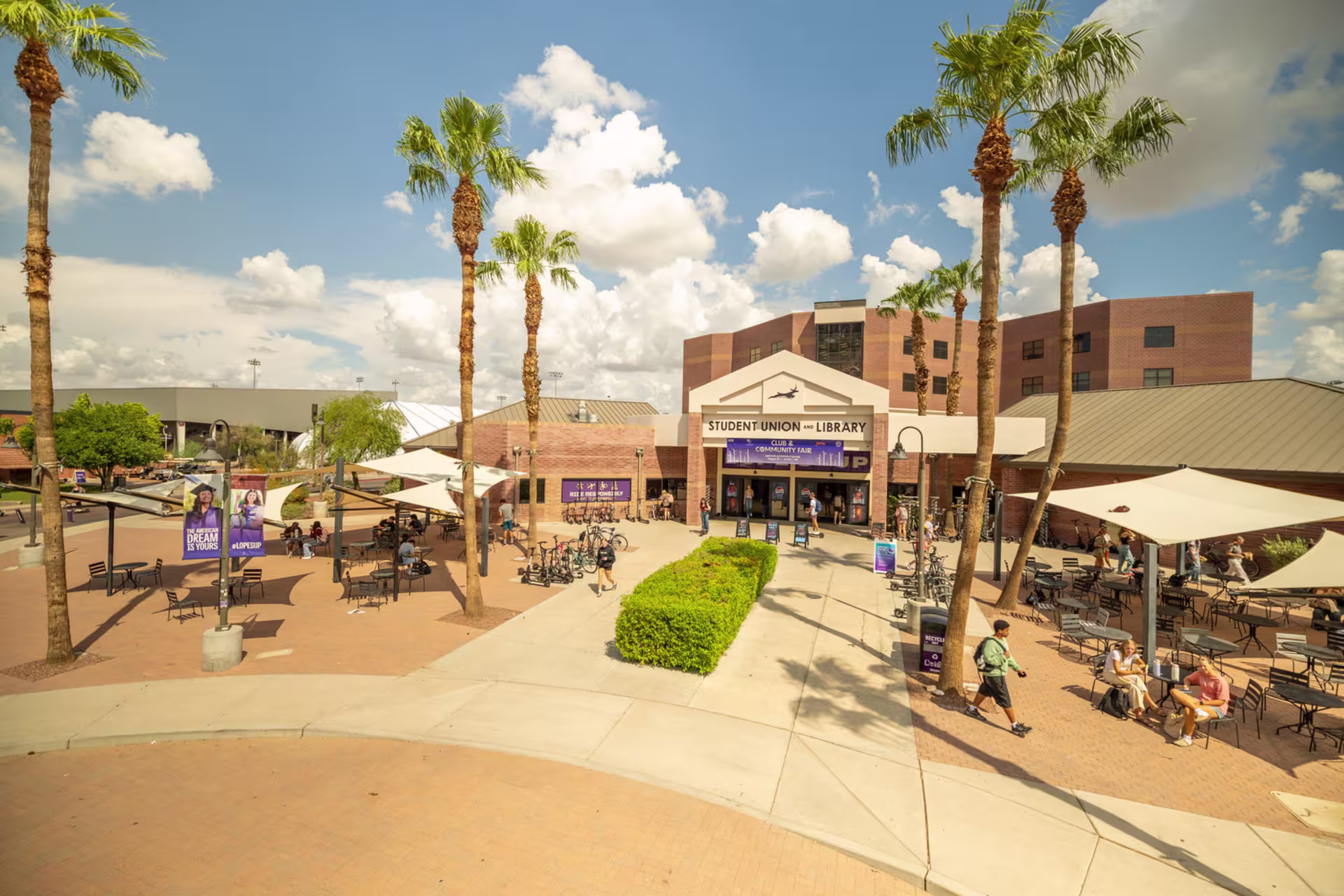 Students dining and gathering outside the GCU Student Union with palm trees, shaded seating and a lively campus atmosphere.