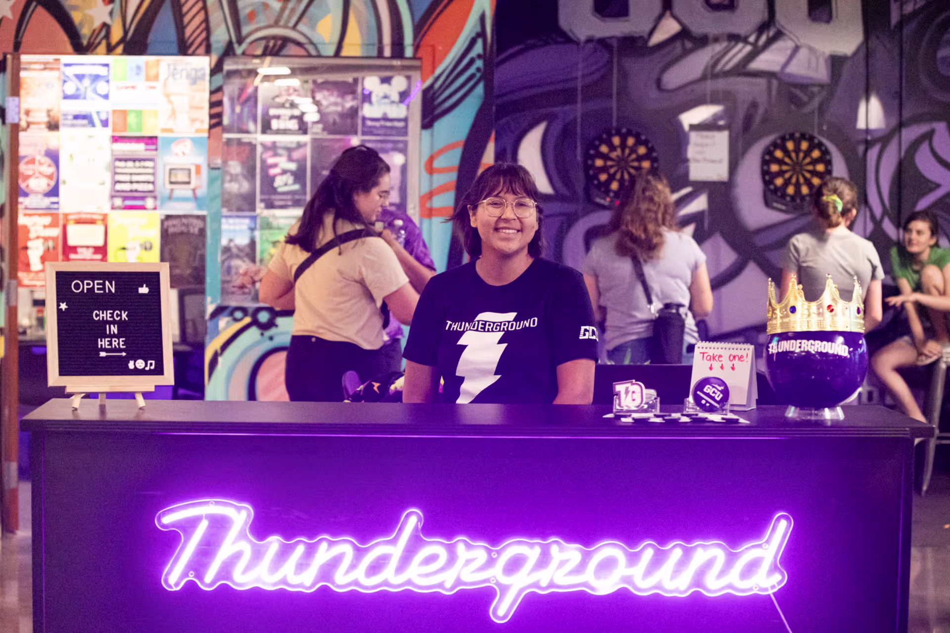 GCU student at the Thunderground with neon signage, games and a vibrant social hangout space on campus.