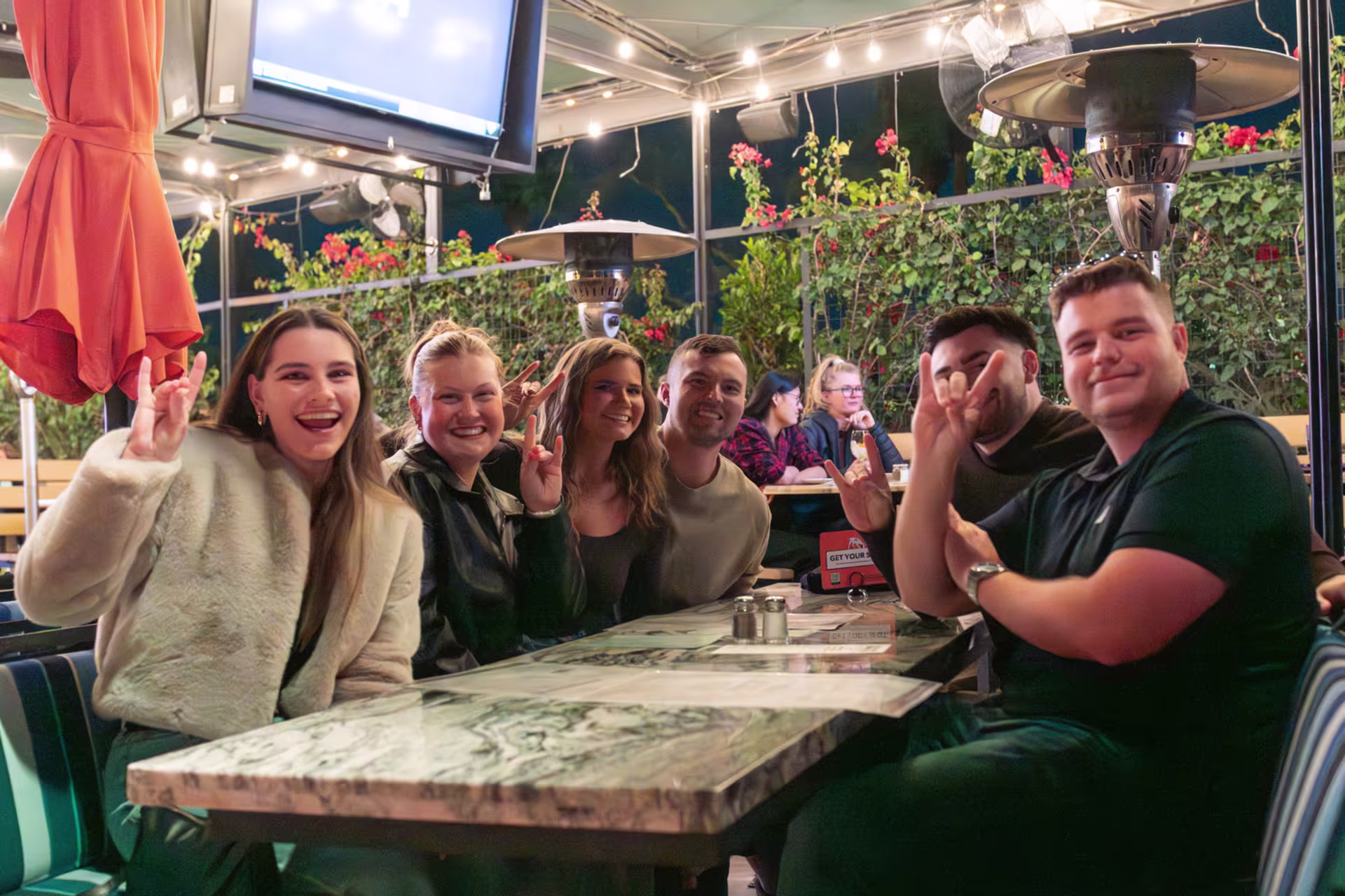 GCU students enjoying a meal together at an outdoor campus dining area, smiling and socializing in a lively evening setting.