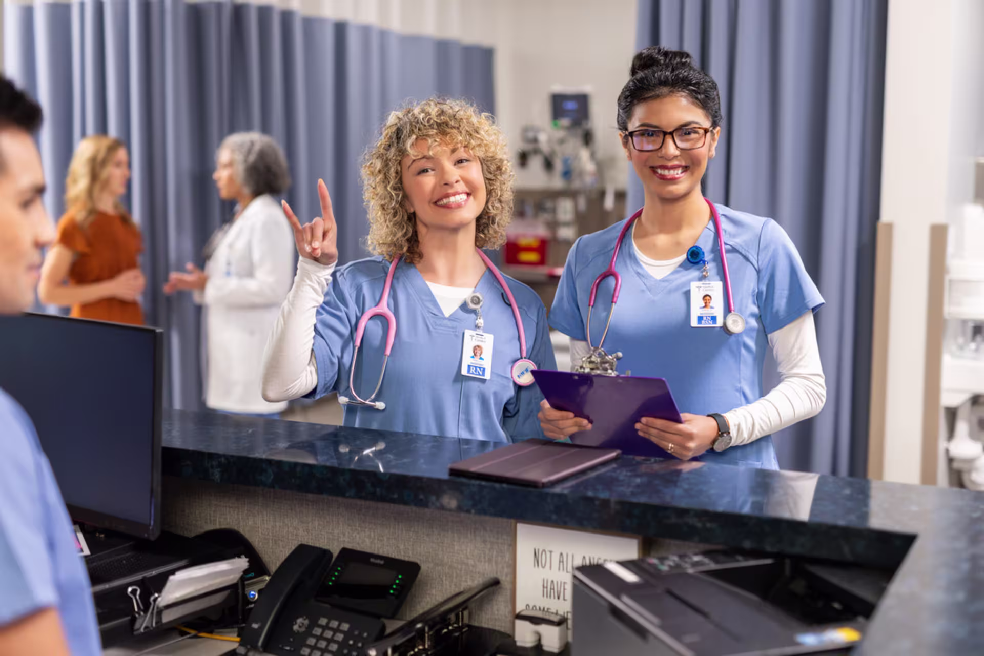 MSN nursing students with stethoscopes collaborate at a nurses’ station with patient charts.