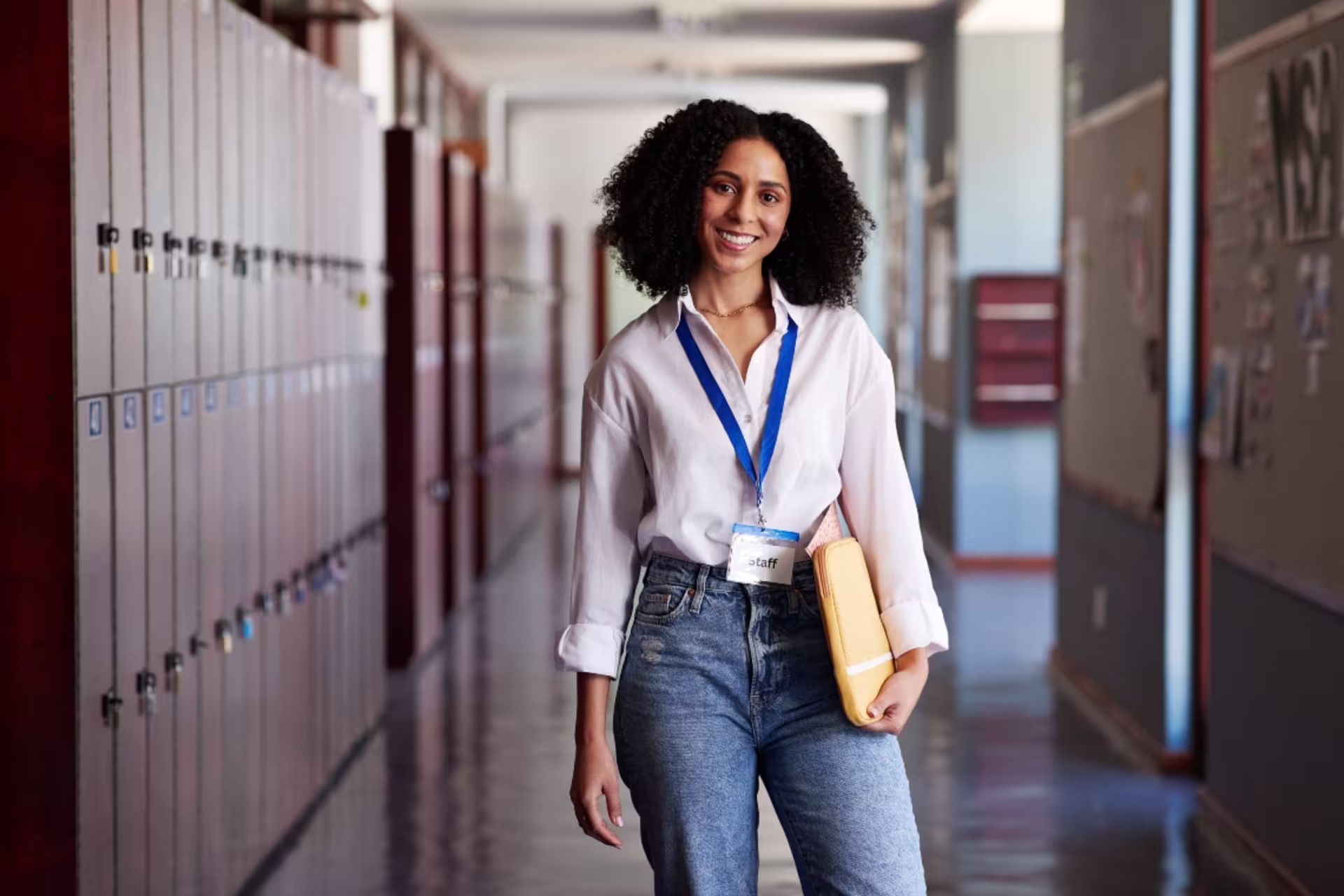 Smiling female history professor standing with a file folder in the corridor.