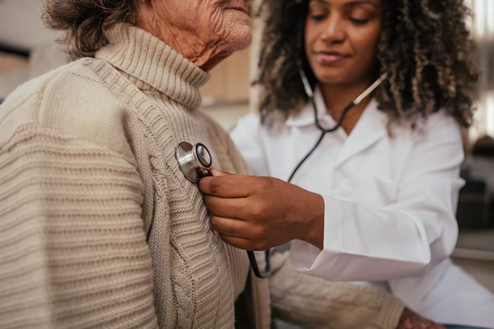 Female doctor demonstrating healthcare quality by performing assessment on elderly female patient’s lungs with stethoscope.
