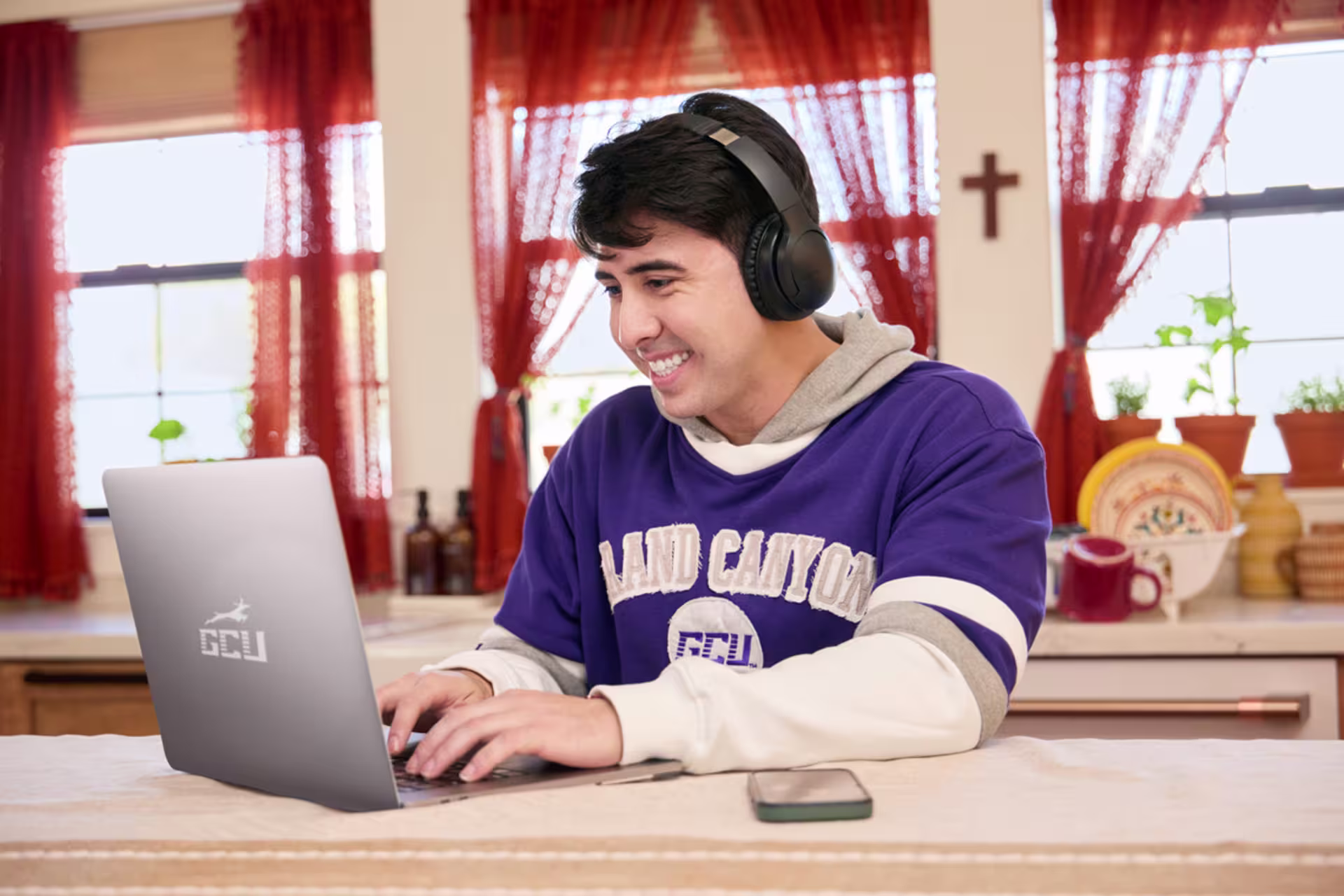 Student attending an online master’s in education class with a laptop and headphones.