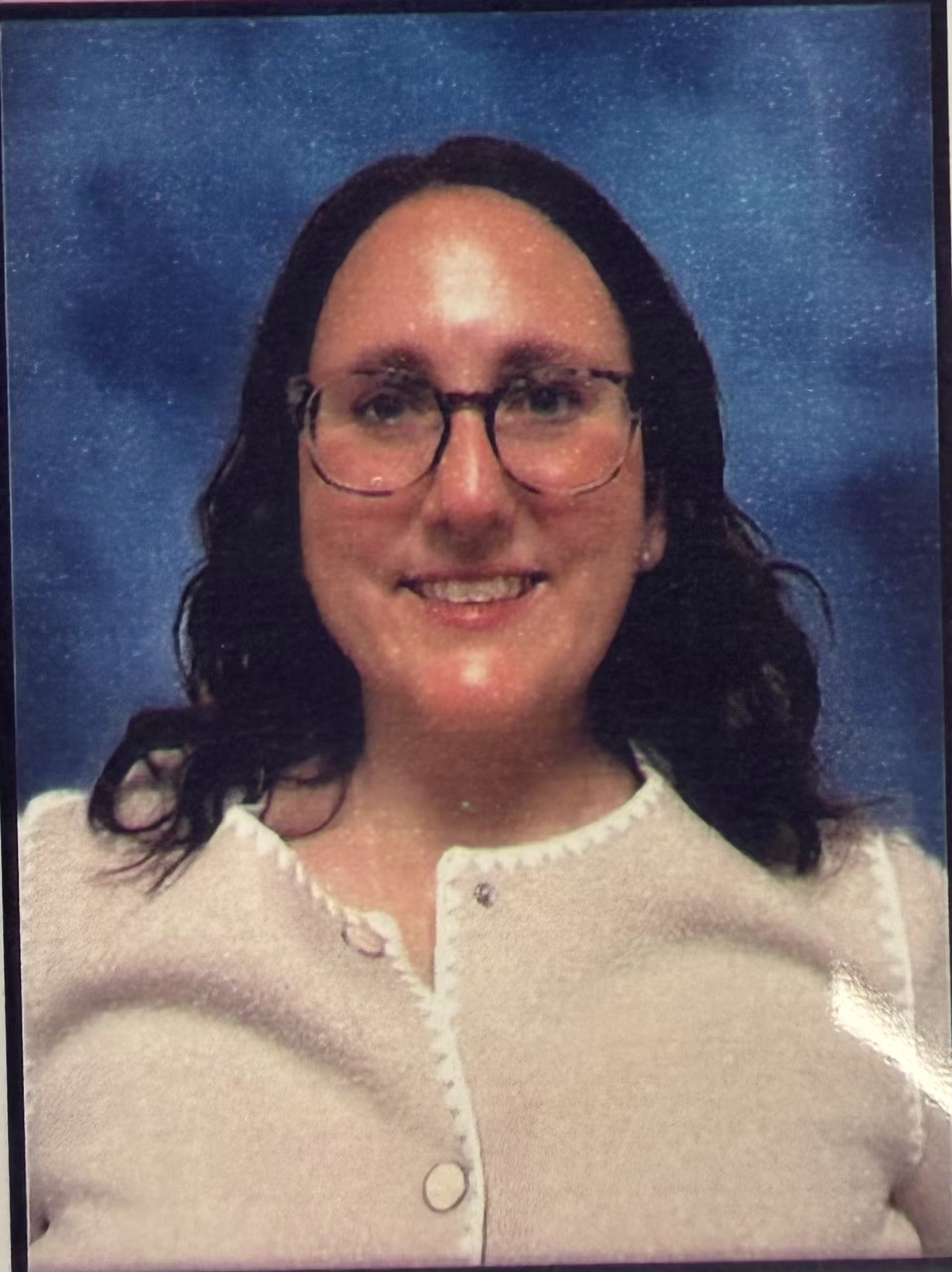Dr. Heidi Phelps, a GCU alumna, is shown in a professional headshot against a blue studio-style background, wearing glasses and a light-toned top that conveys a polished, academic presence.