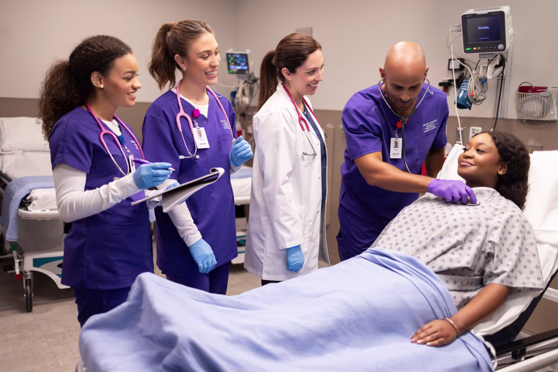 Four Boise area accelerated nursing students and an instructor provide patient care in a clinical simulation lab setting.