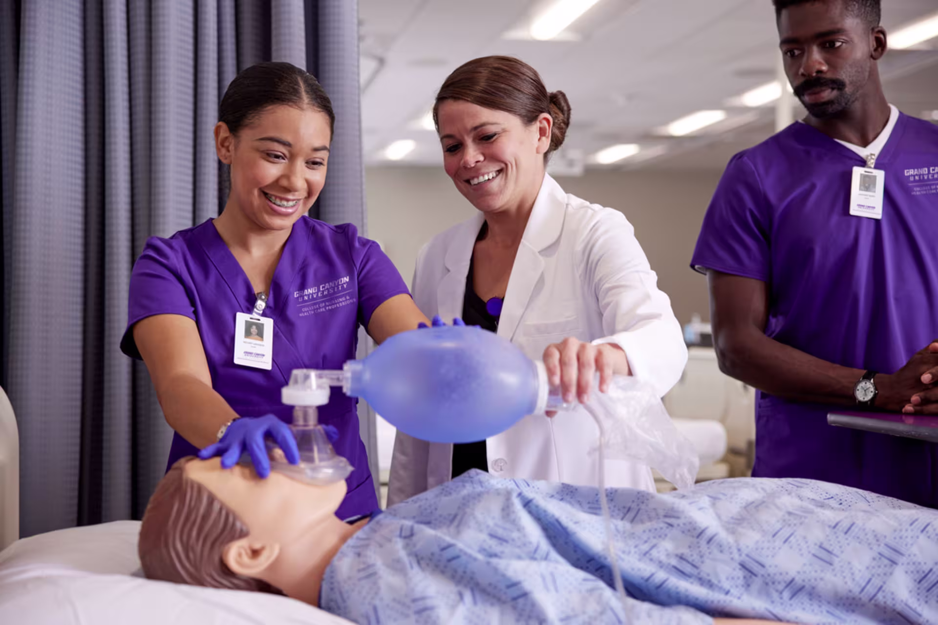 Accelerated BSN students practice ventilation techniques on a simulation manikin under instructor supervision in a clinical lab.