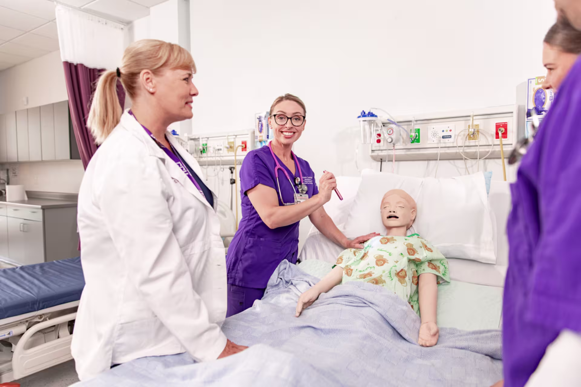 A female accelerated nursing student and an instructor practice patient care skills with a medical manikin in a clinical simulation lab in Florida.