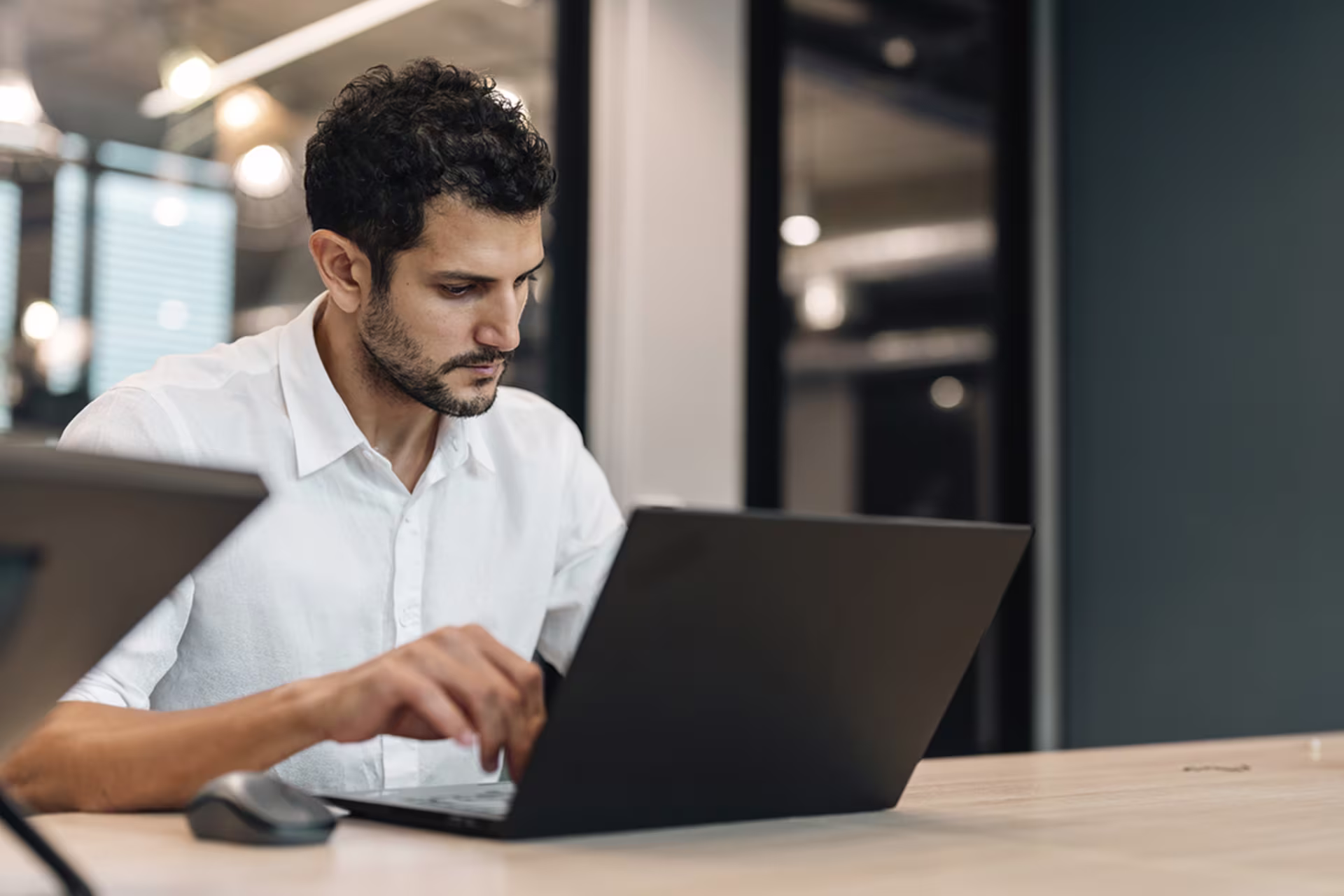 Infrastructure professional working on a laptop in a modern office, focused on productivity, remote work, and digital business operations.