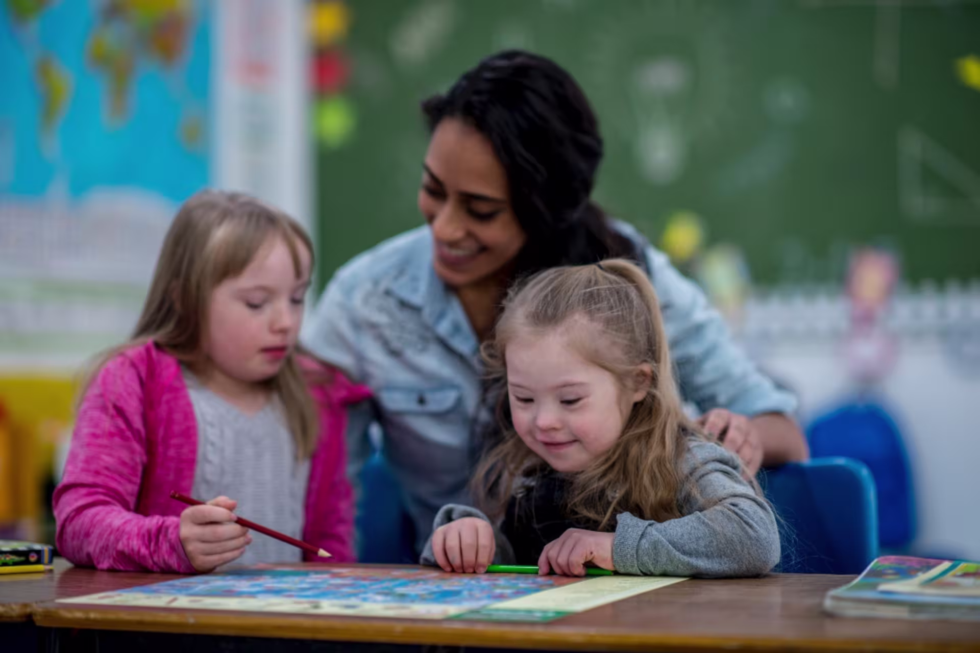 A special education teacher assists young students with a classroom learning activity.