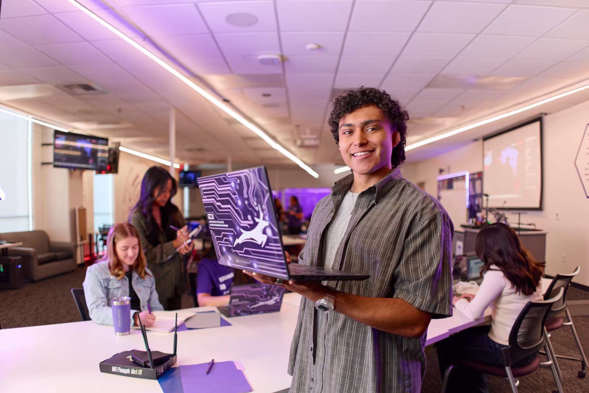IT student worker with a laptop goes to a classroom to check for proper installation of students' MFA access.