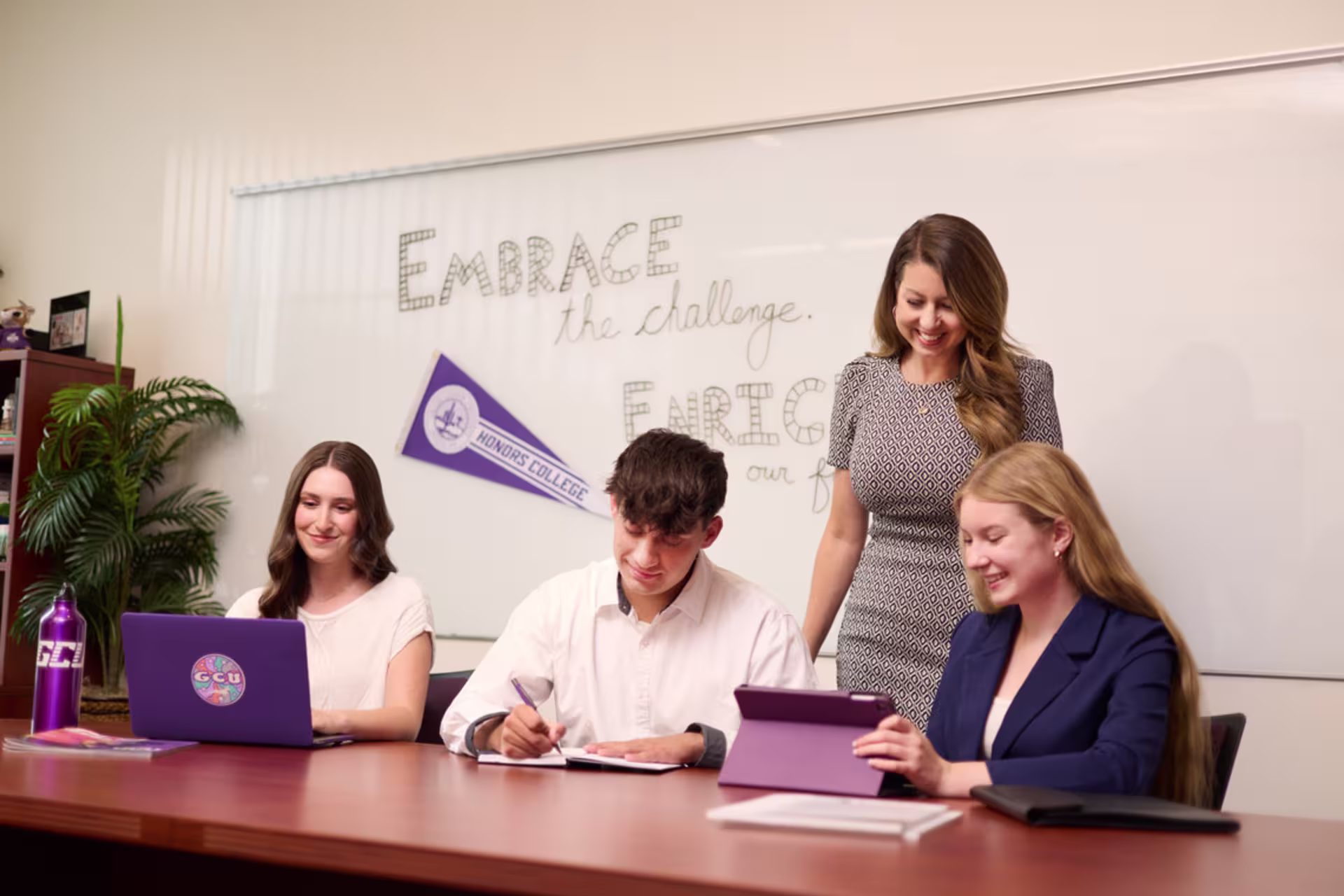 Human resource management students dressed in business casual attire working on coursework at desk in class setting.
