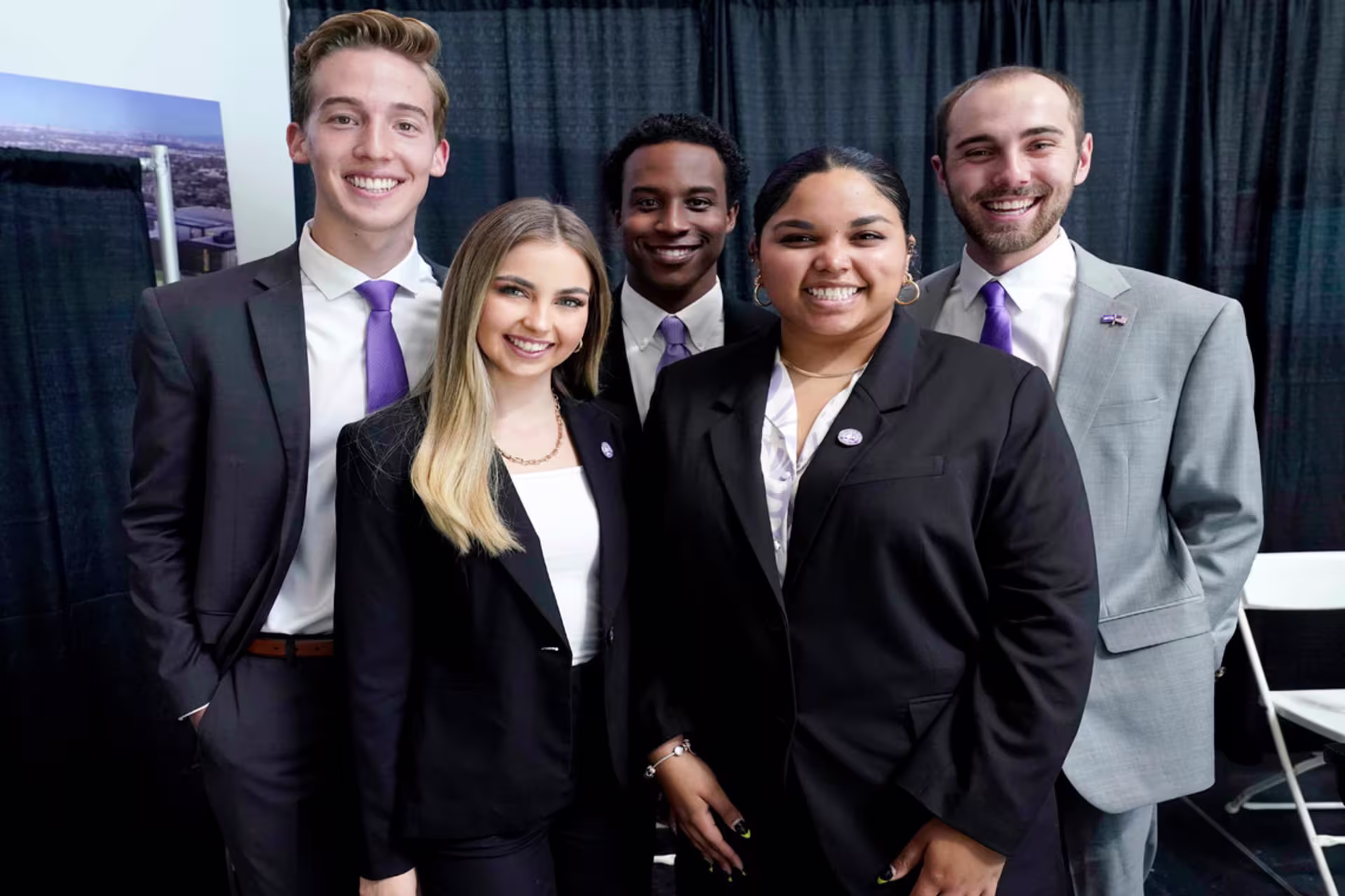 Business students pose together in professional attire at a networking event.