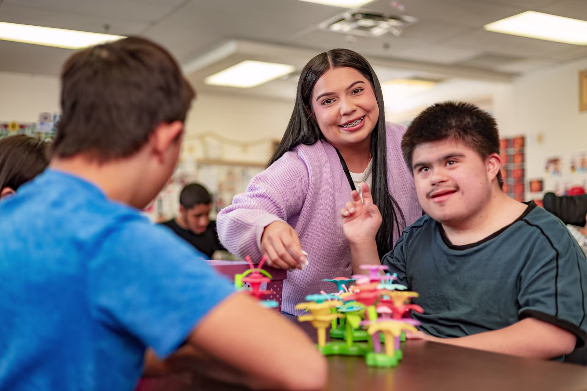 Female bachelor’s in special education degree student smiling while supporting diverse learners during a classroom activity.