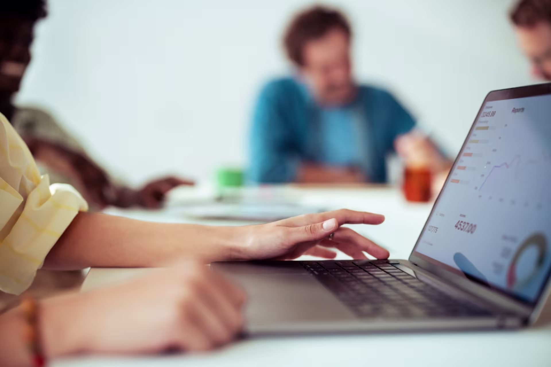 A project management student reviews analytics on a laptop during a group meeting.