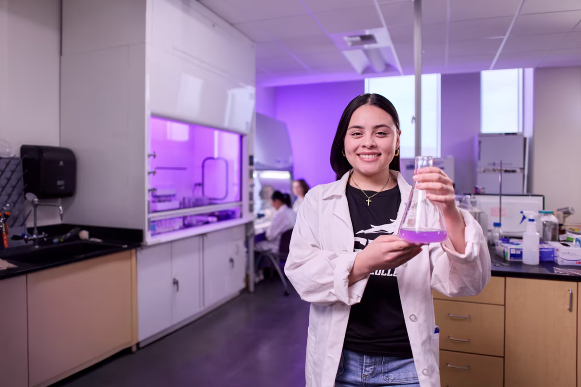 A female biology student holds a flask during a laboratory experiment.