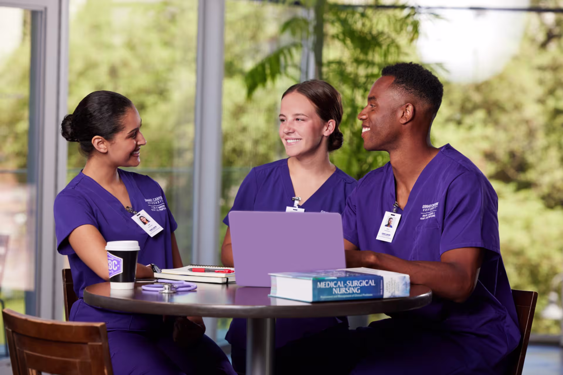 ABSN nursing students study together with a laptop and medical textbook.