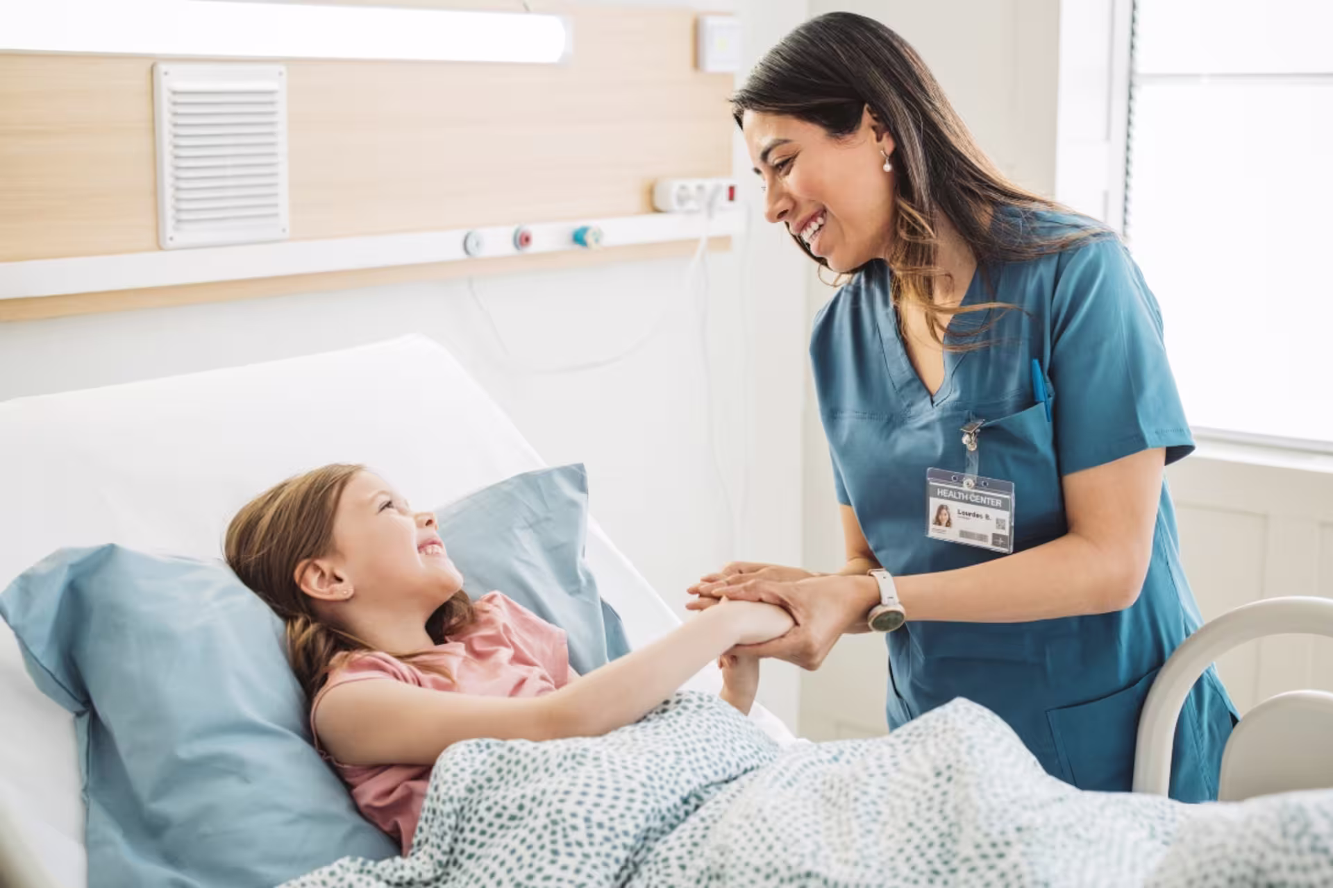 A pediatric nurse comforts a young patient during a hospital stay.