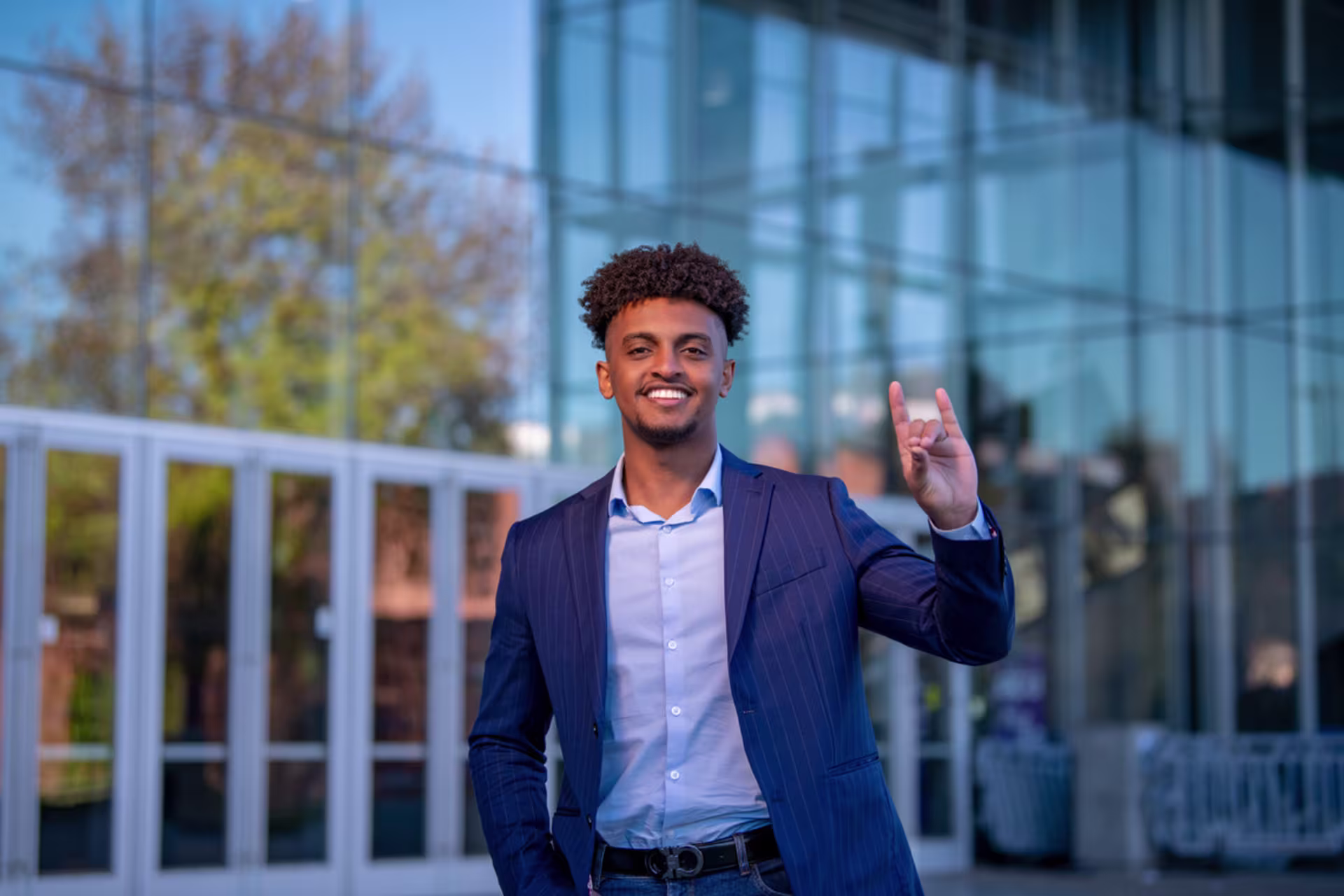 Business student celebrating outside a modern campus building.