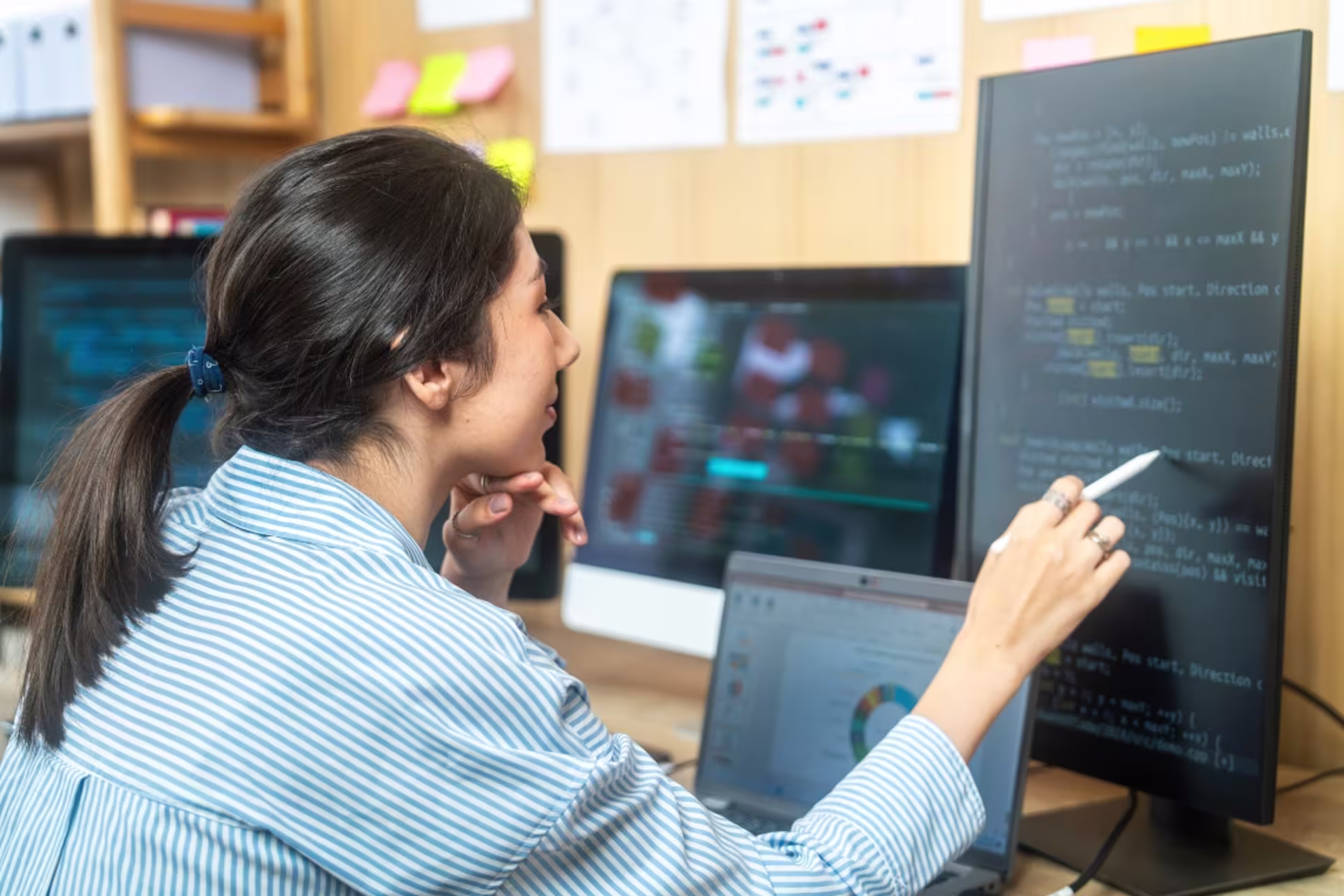 A data science graduate student analyzes code and data visualizations on multiple computer screens.
