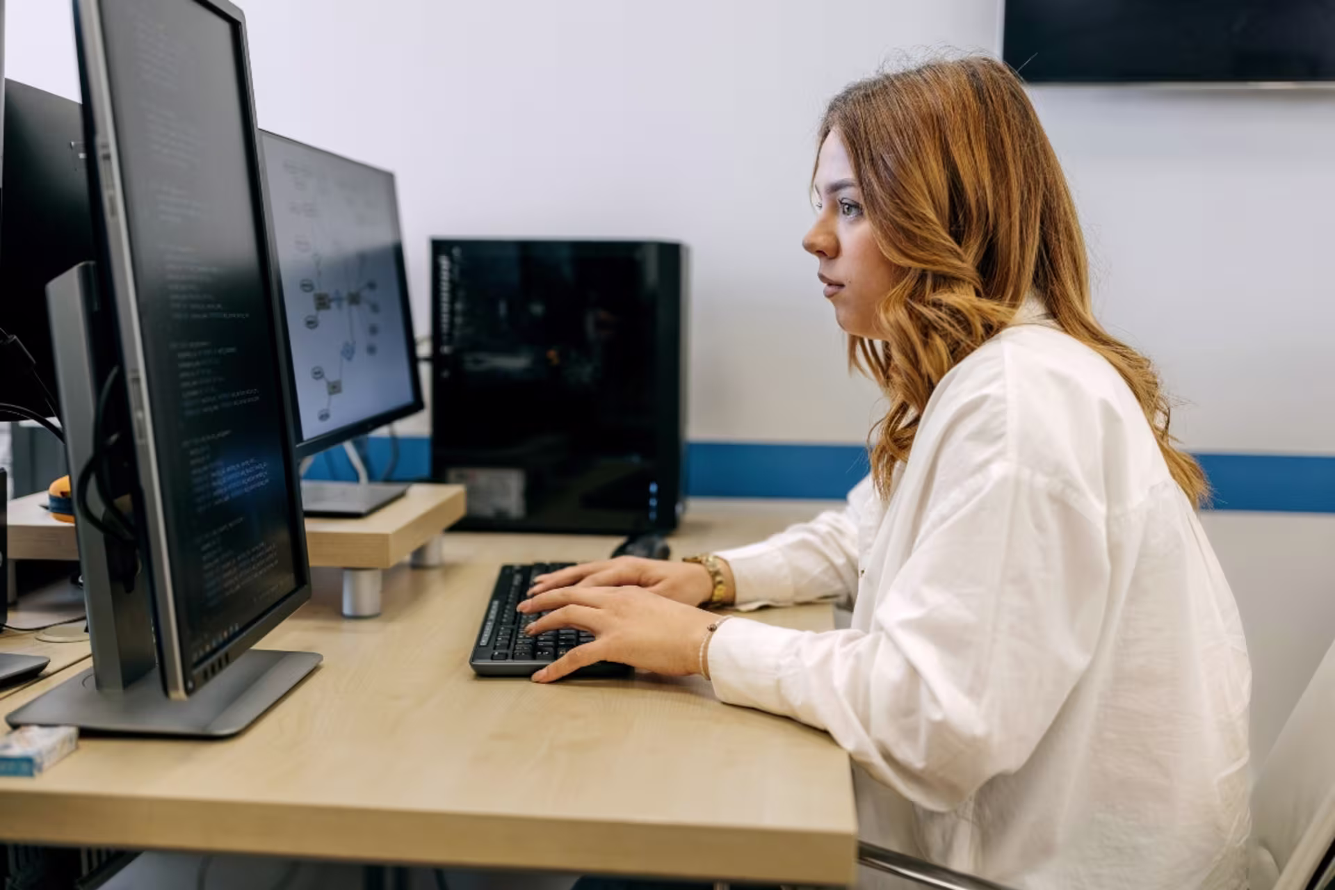 A data science graduate student writes code and analyzes datasets on multiple computer monitors.