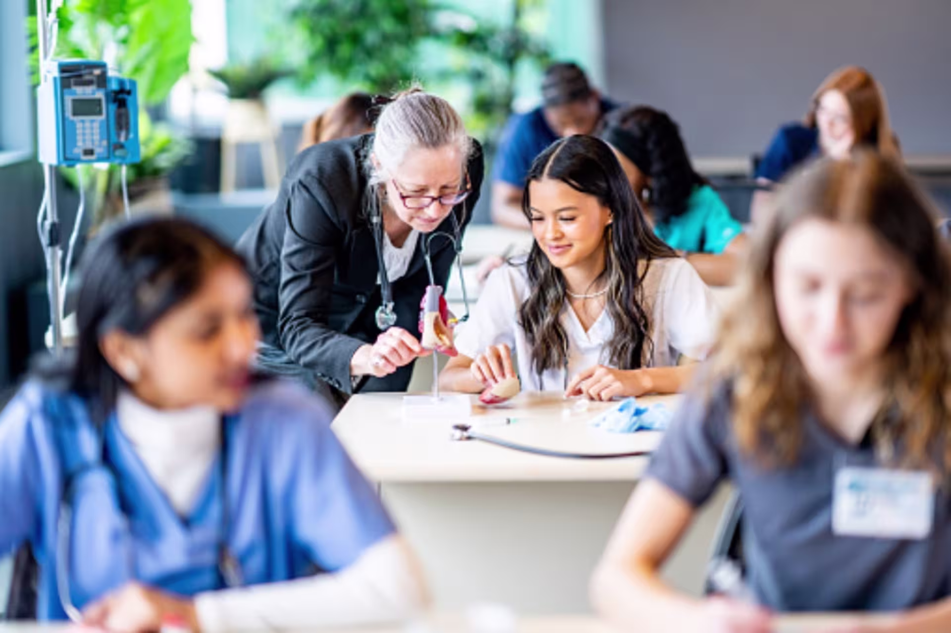 A nursing educator guides a student through a clinical training activity during classroom instruction.