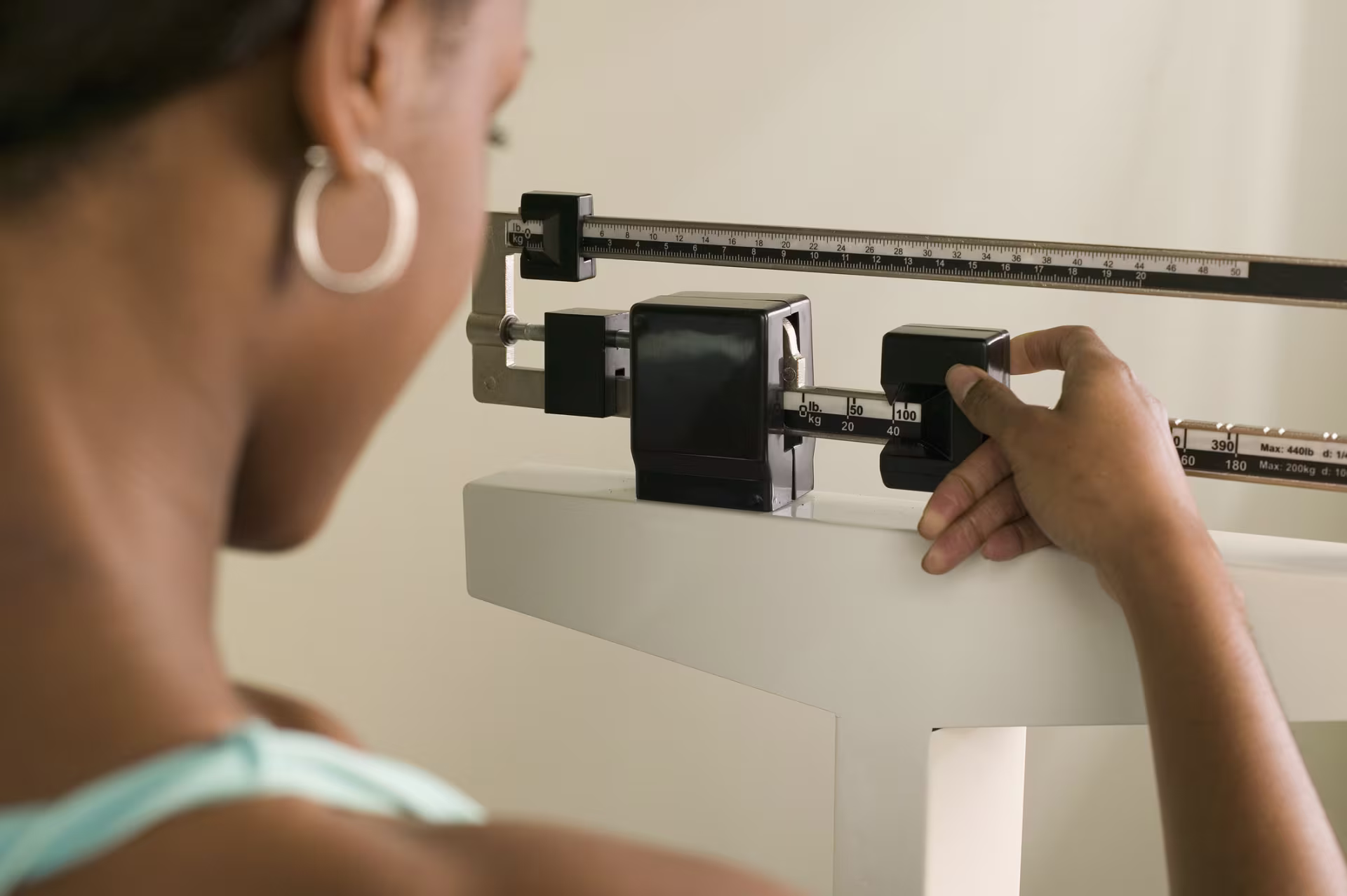 Person adjusting a medical balance scale during a weight check, illustrating obesity measurement, prevention awareness and overall health.