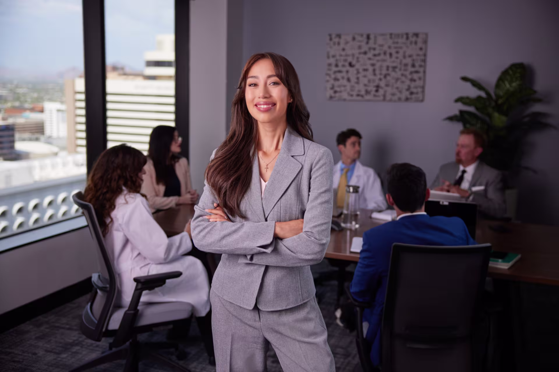 A health administration student stands in a boardroom.