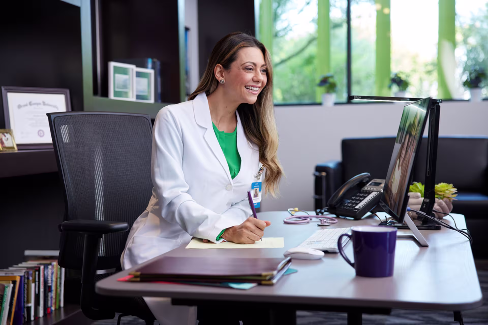 Female health administration professional working at a desk in a medical office.