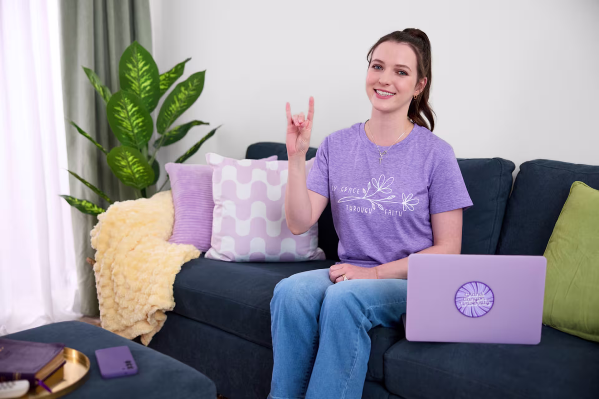 Online female health administration student working from home on a couch with a purple laptop.