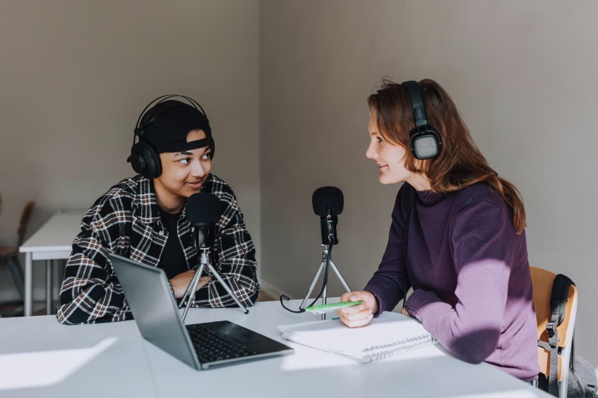 Social media students record a podcast together with microphones and a laptop.