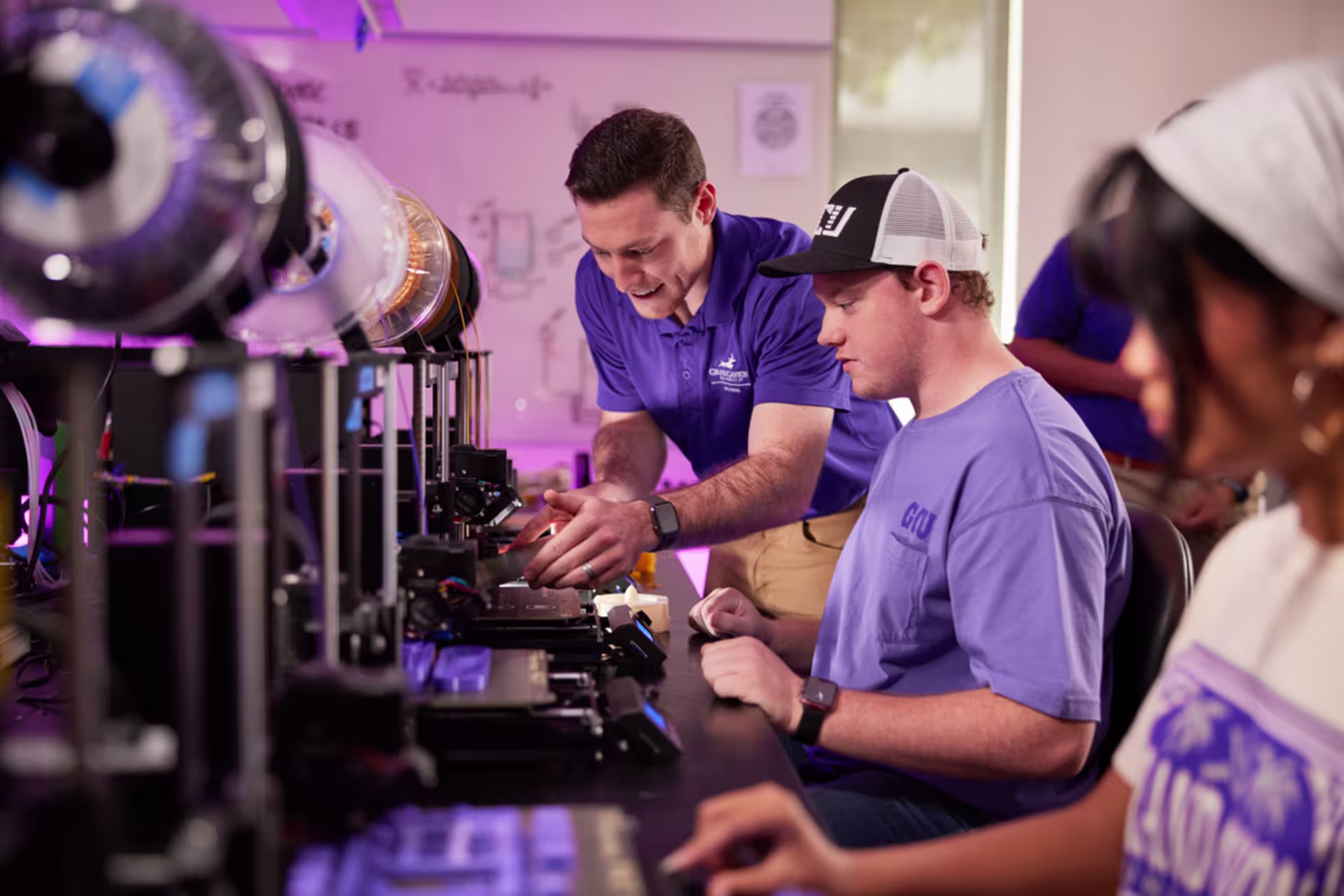 Engineering Masters students getting help from professor during a lab.