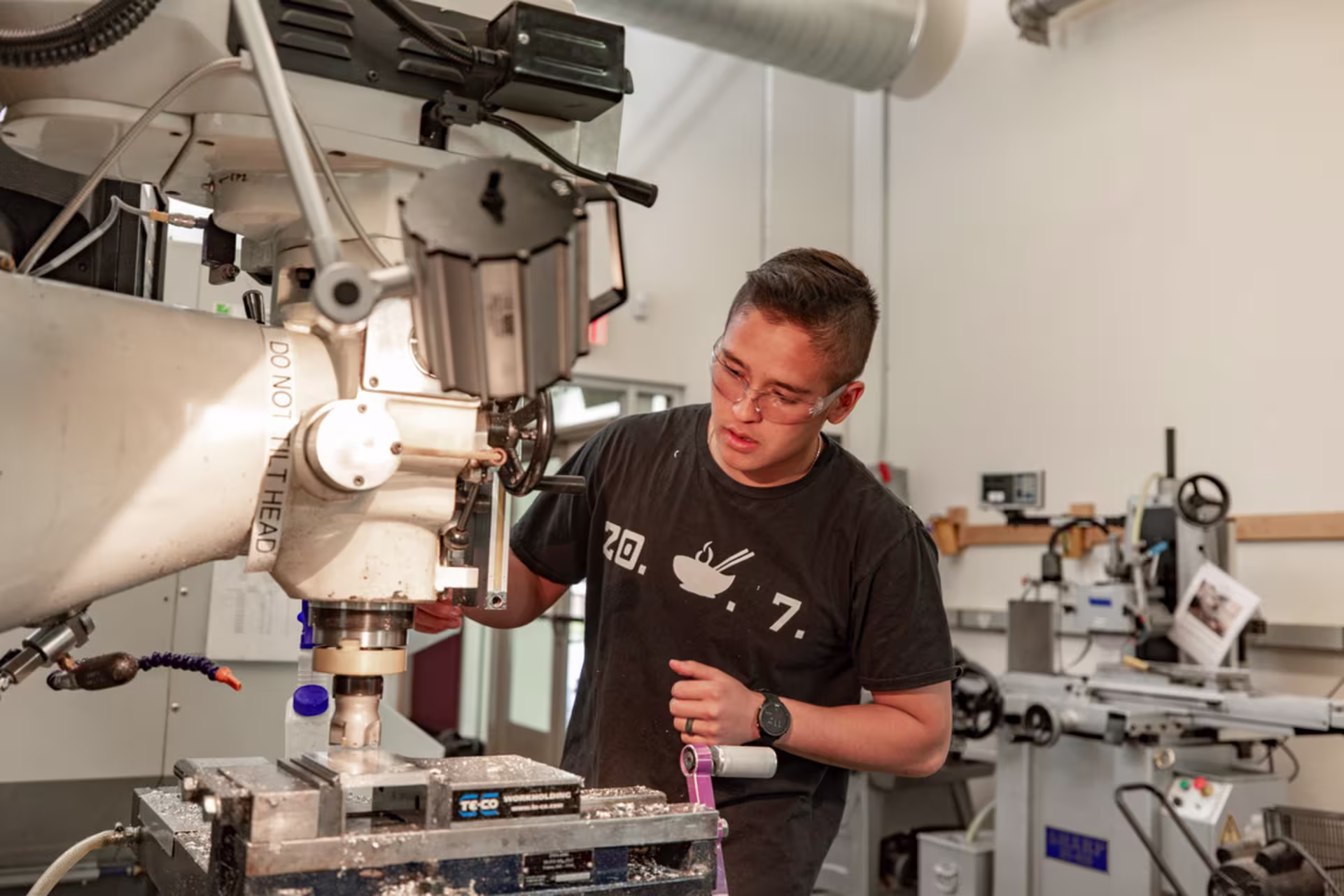 Male mechanical engineering student operating a milling machine.