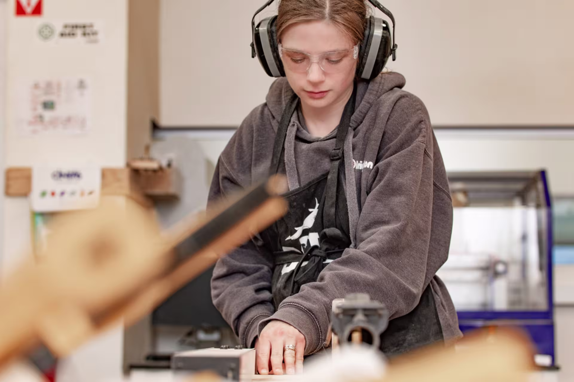 Female mechanical engineer operating equipment while wearing safety gear.