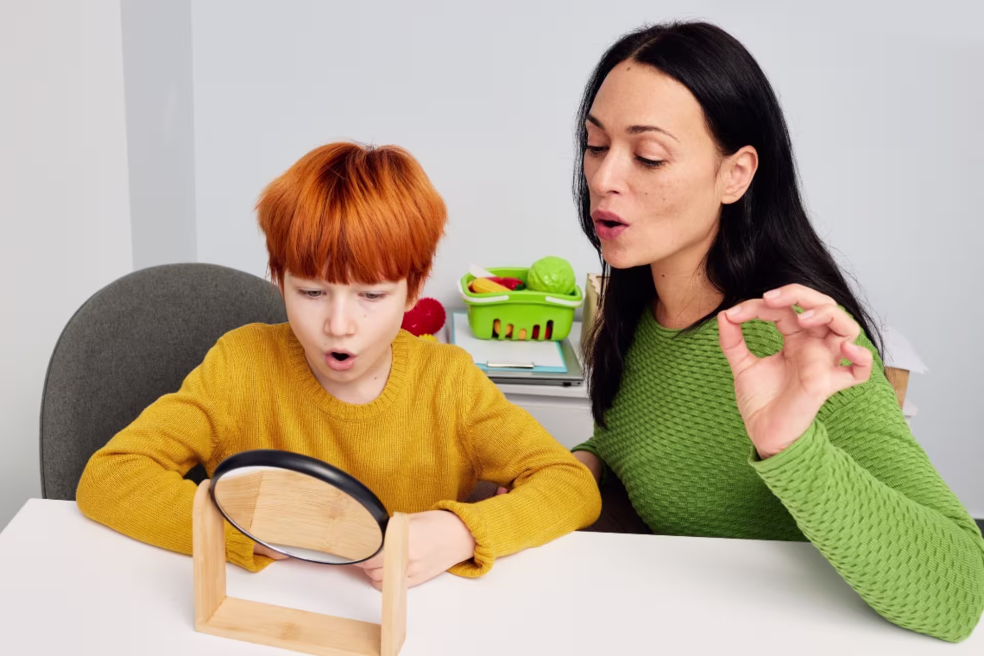 Female speech language pathology professional guiding a child through a speech exercise.