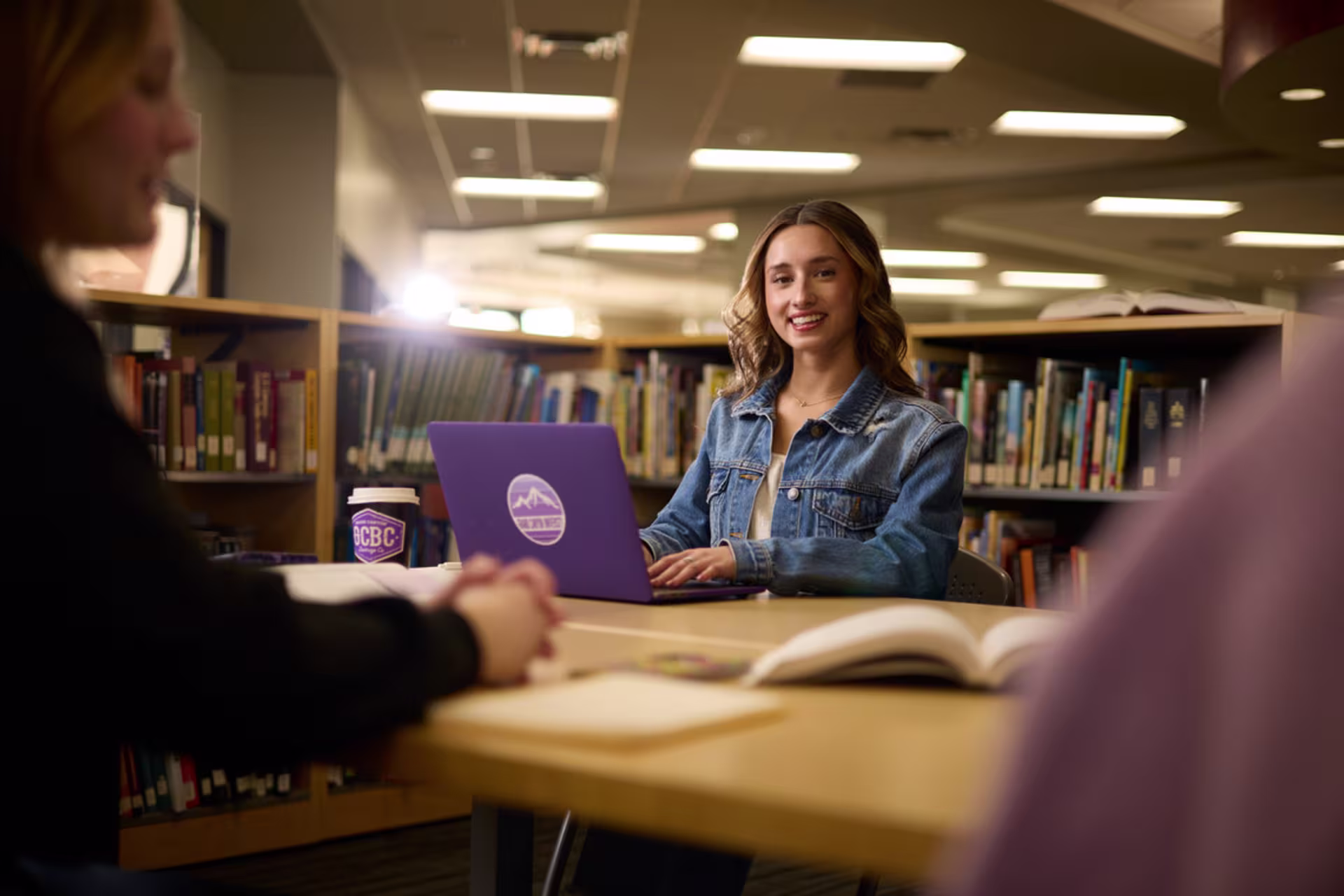 Female speech-language pathology student studying online in a library.