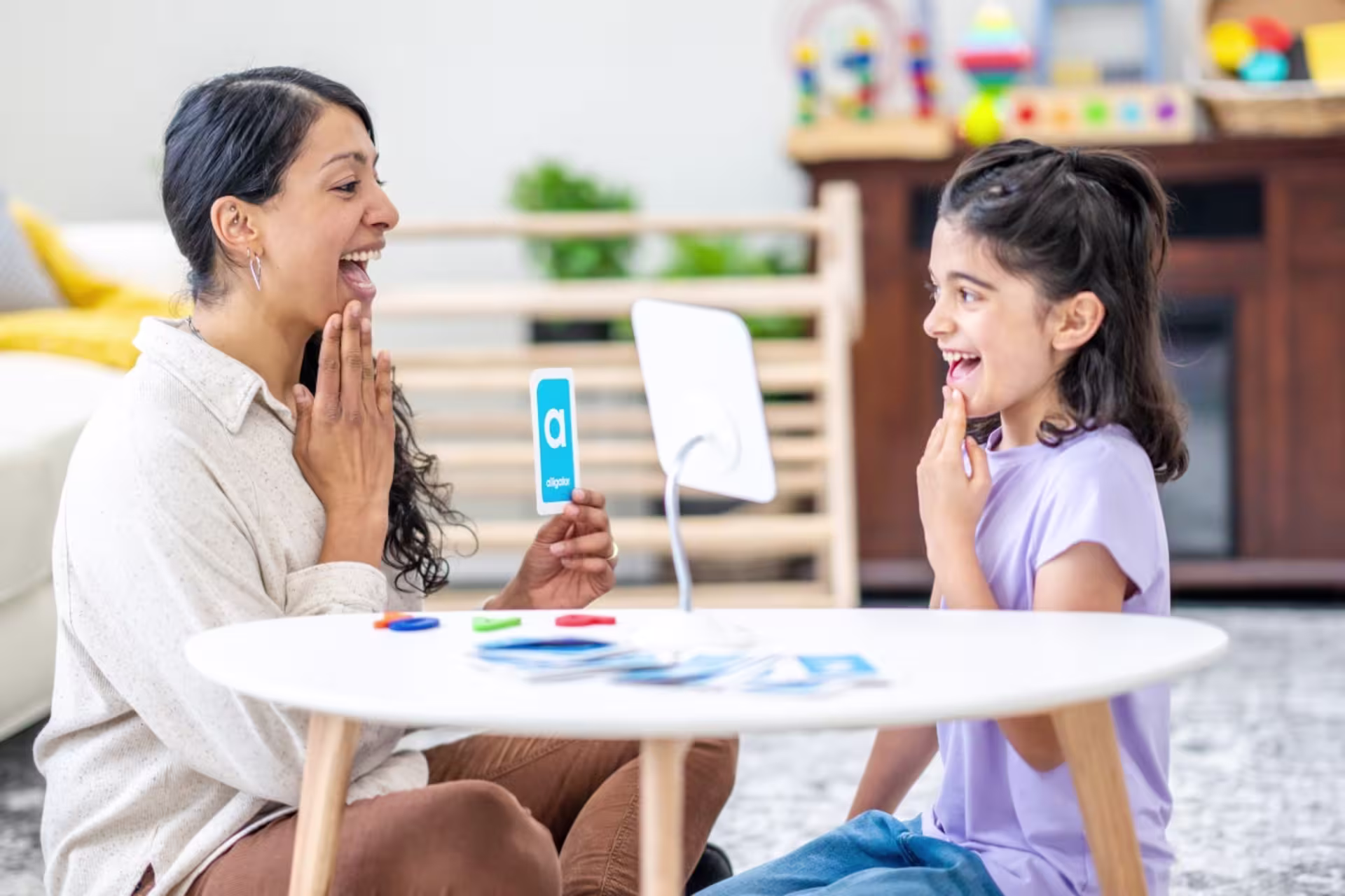 Female speech language pathology professional practicing speech sounds with a child.