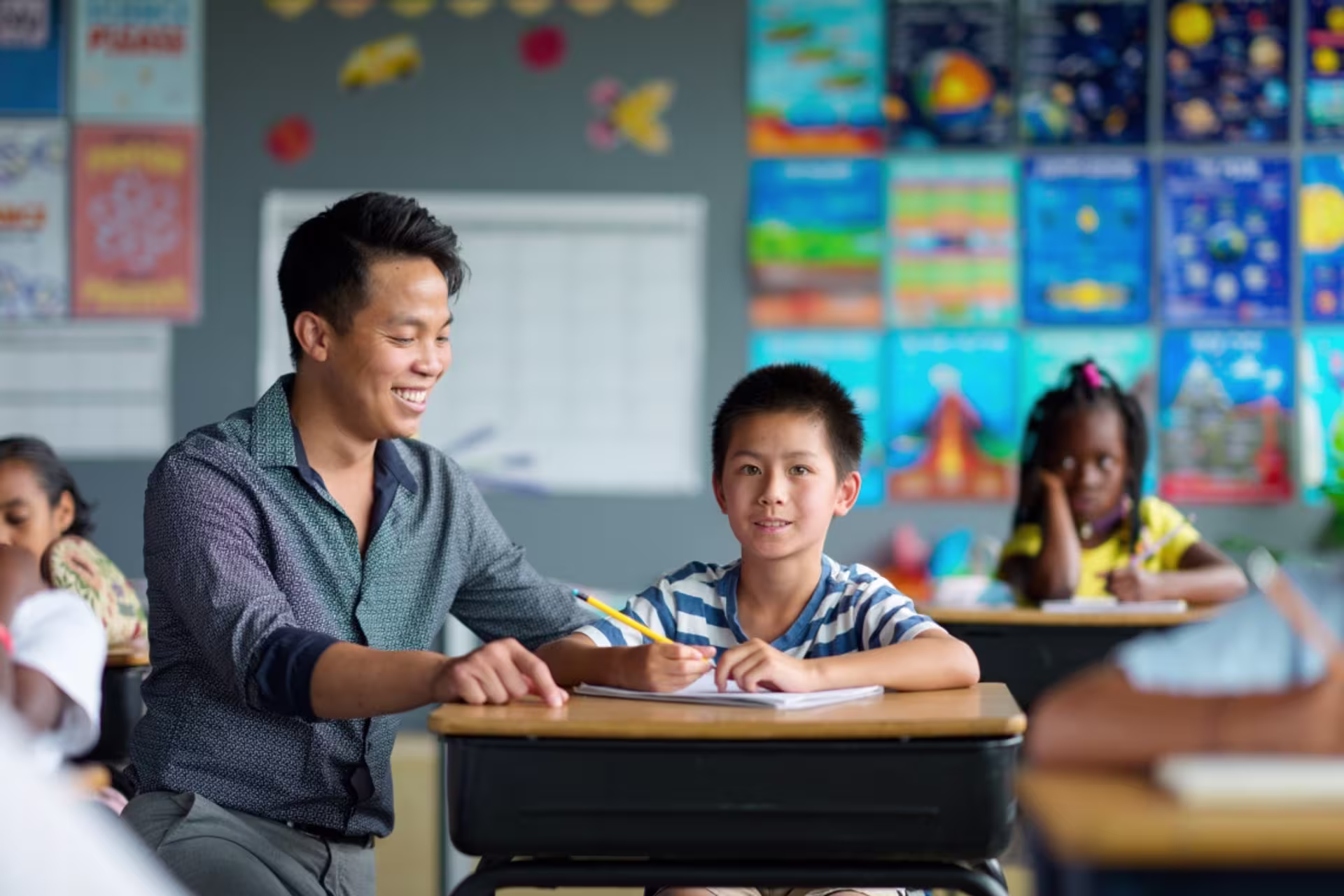 A teacher helps an elementary student during a classroom lesson.