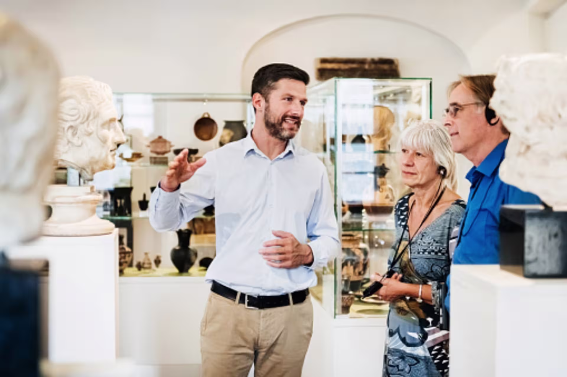 A museum guide explains sculptures to visitors during a gallery tour.