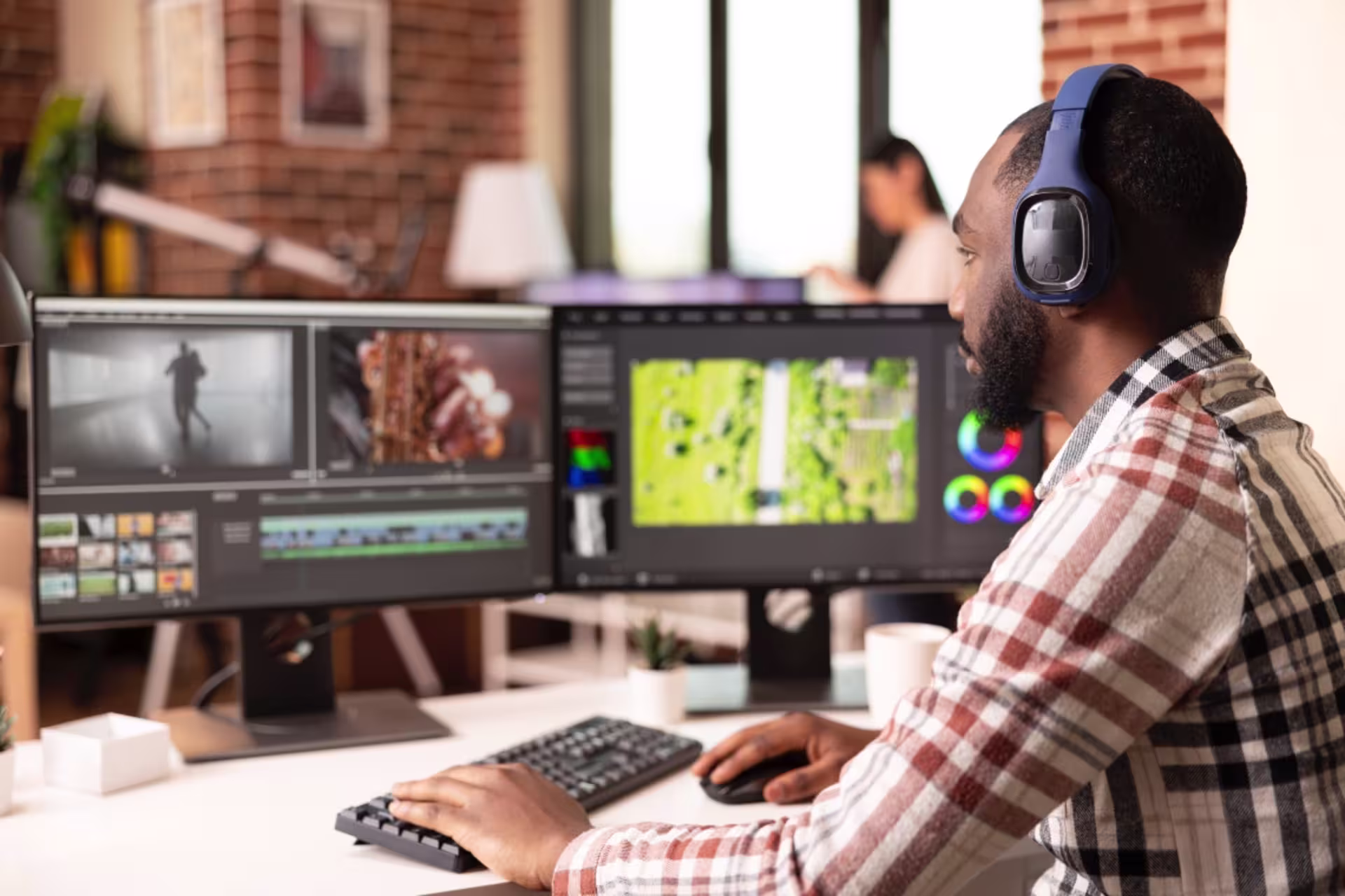 A male video editor edits footage on dual monitors.