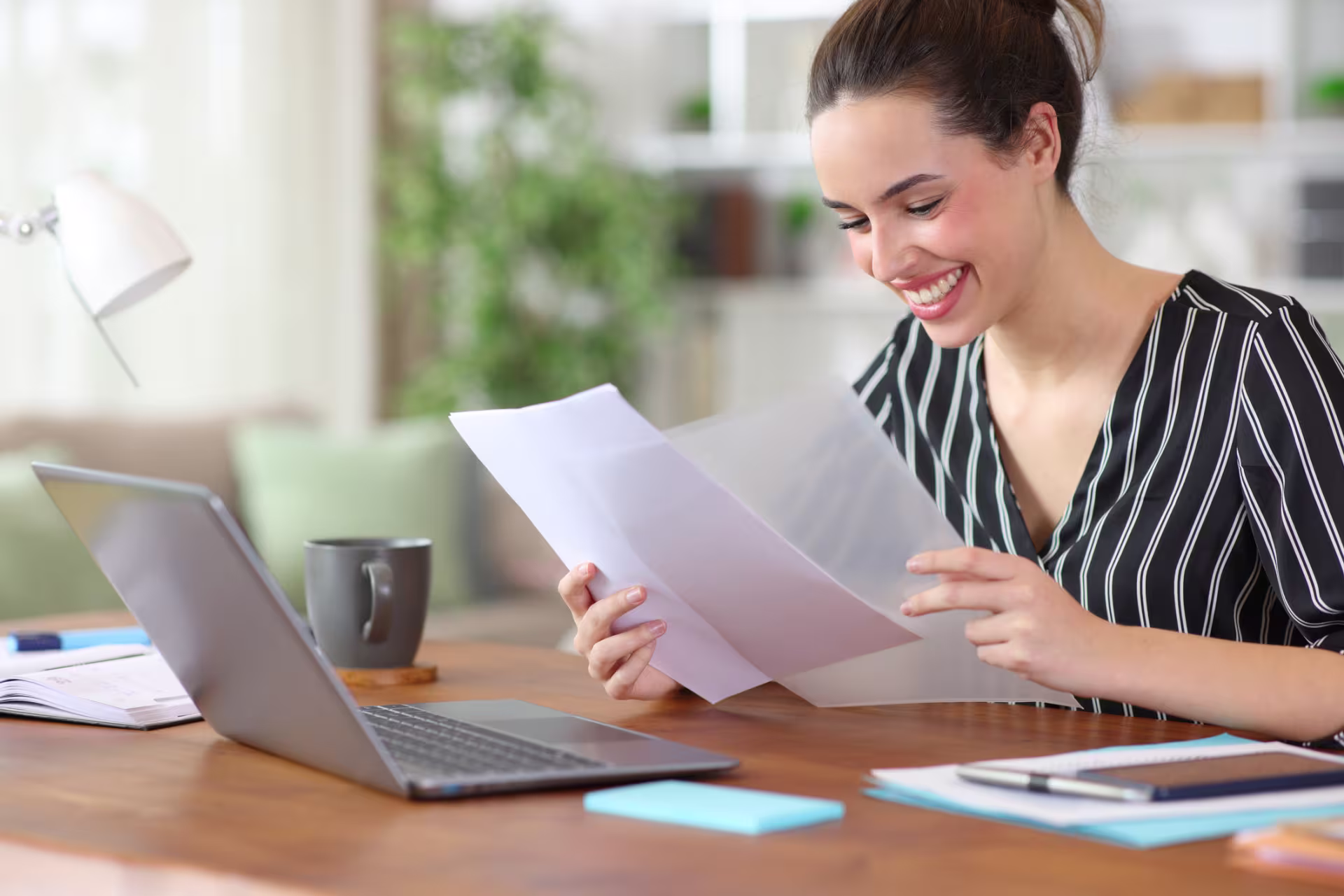 A female business administration student smiles while reviewing documents at a desk.
