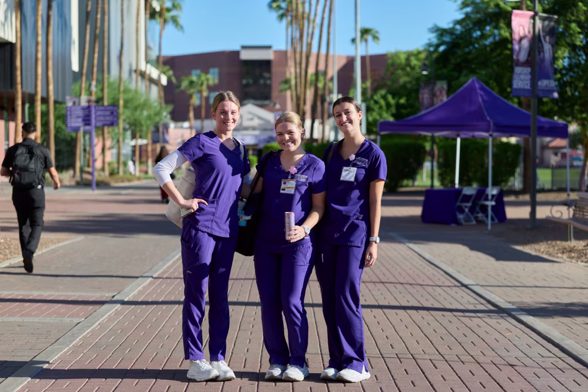 Female nursing students in purple GCU scrubs standing together on campus.