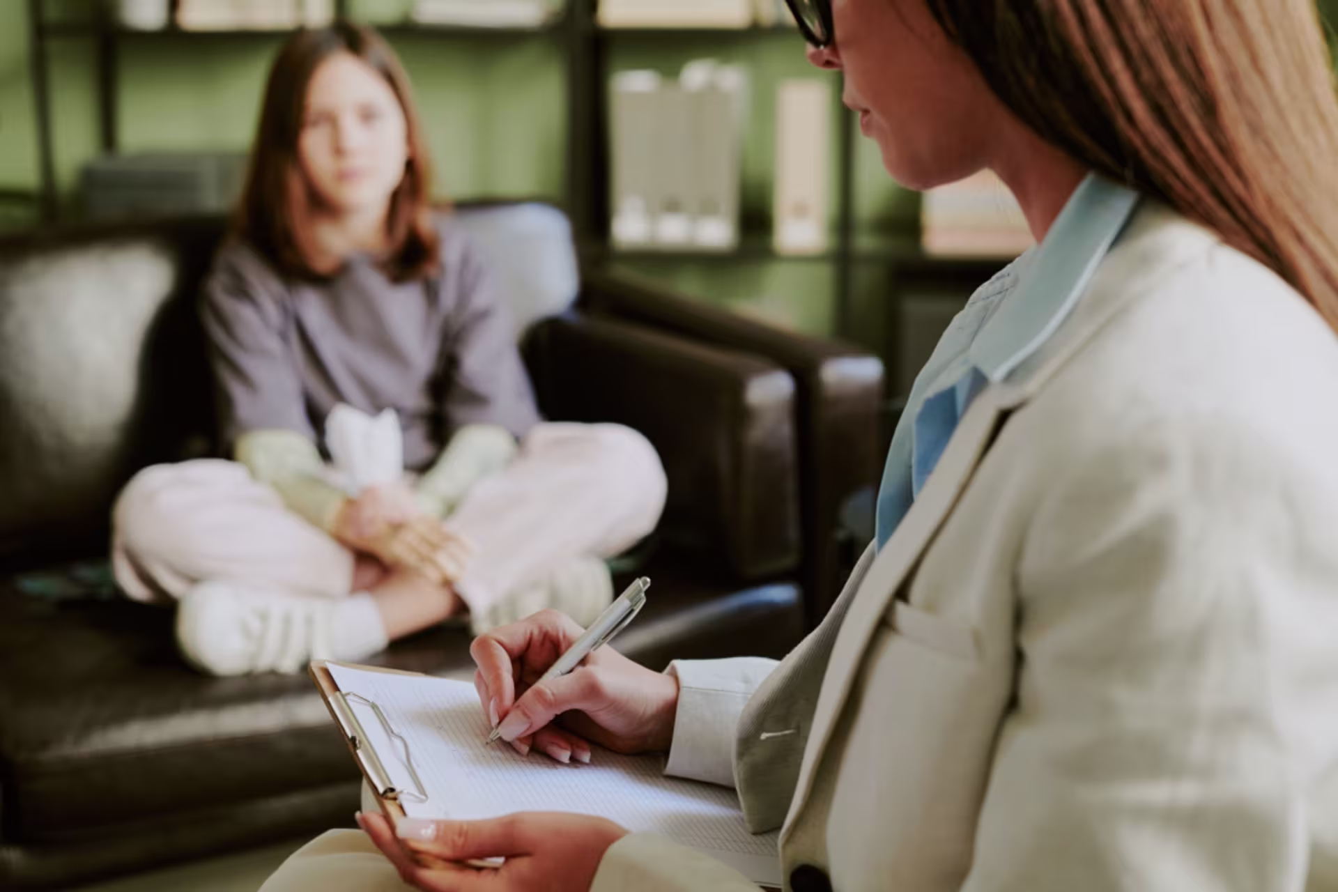 Counseling degree student taking notes during a one-on-one counseling session.
