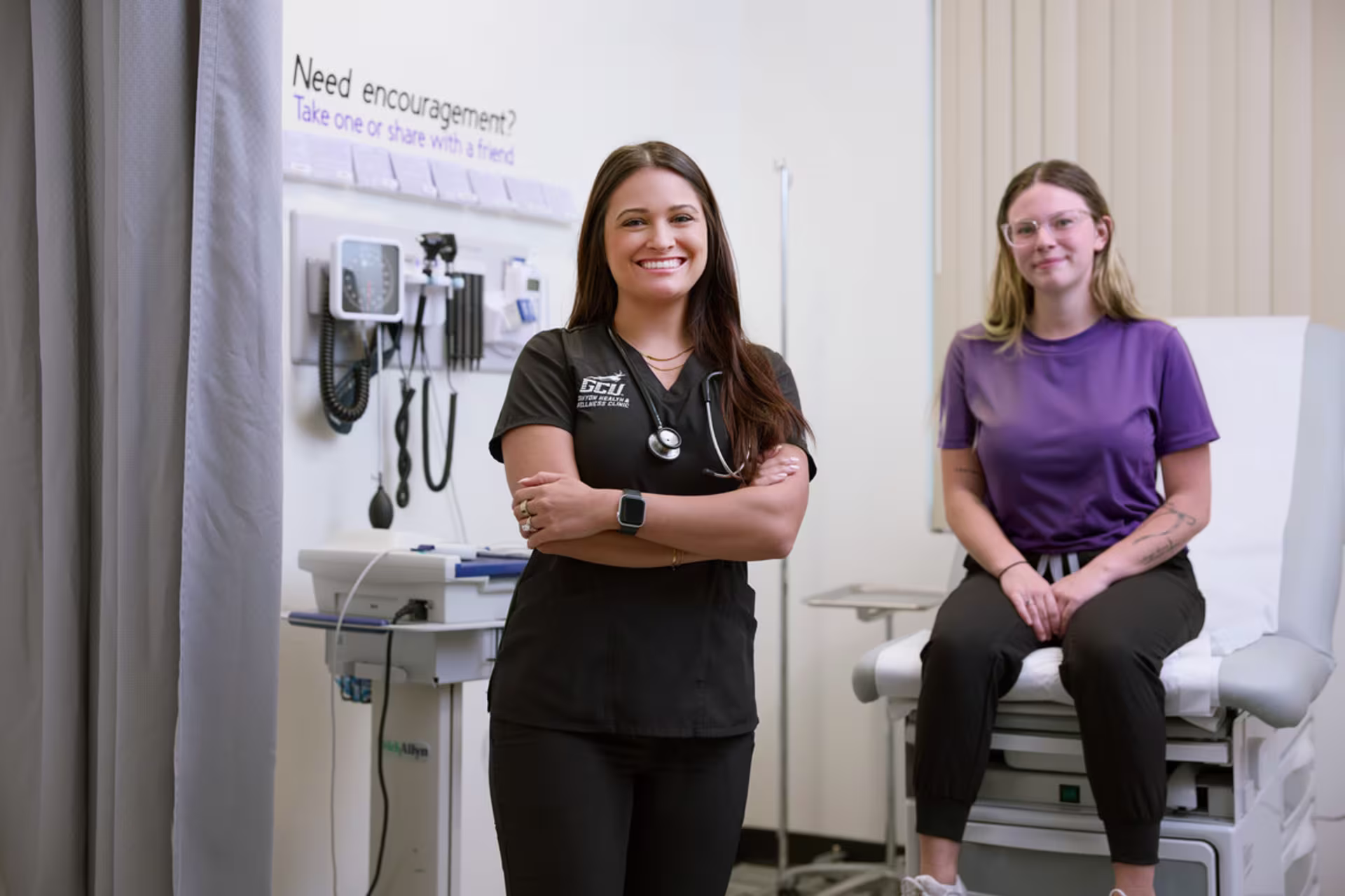 Female pre-med student learning clinical skills posing in a medical exam room.