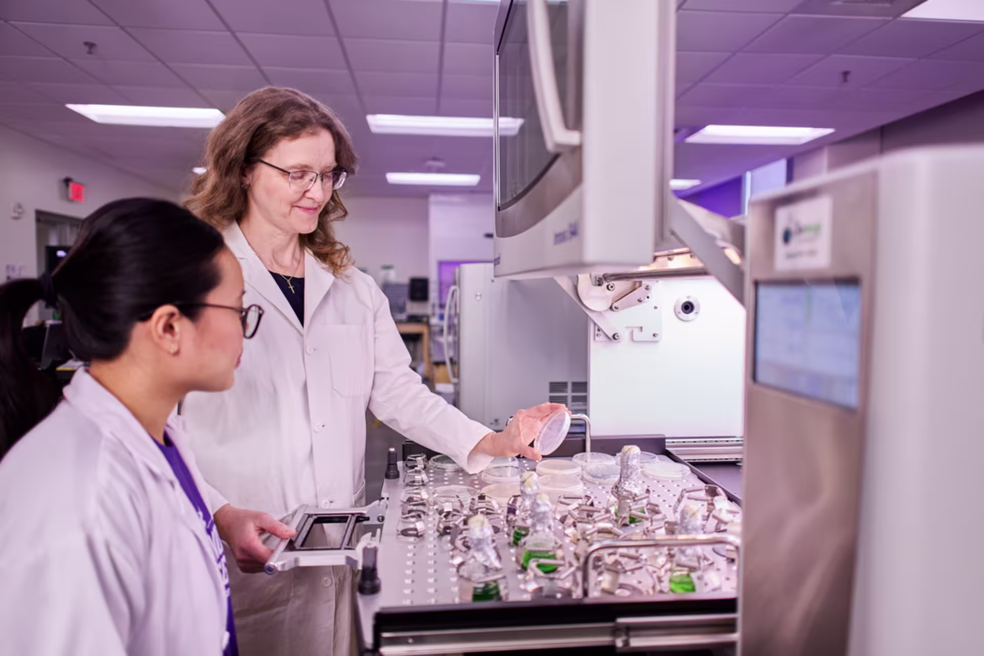 Female biology student and instructor conducting laboratory research.
