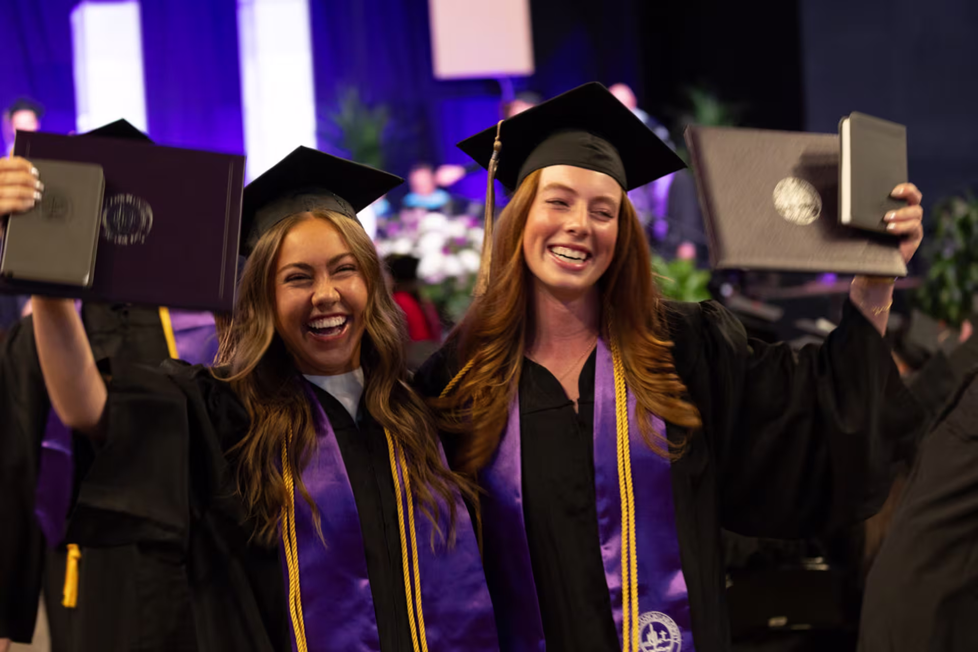 Divinity program graduates holding their diplomas during commencement.
