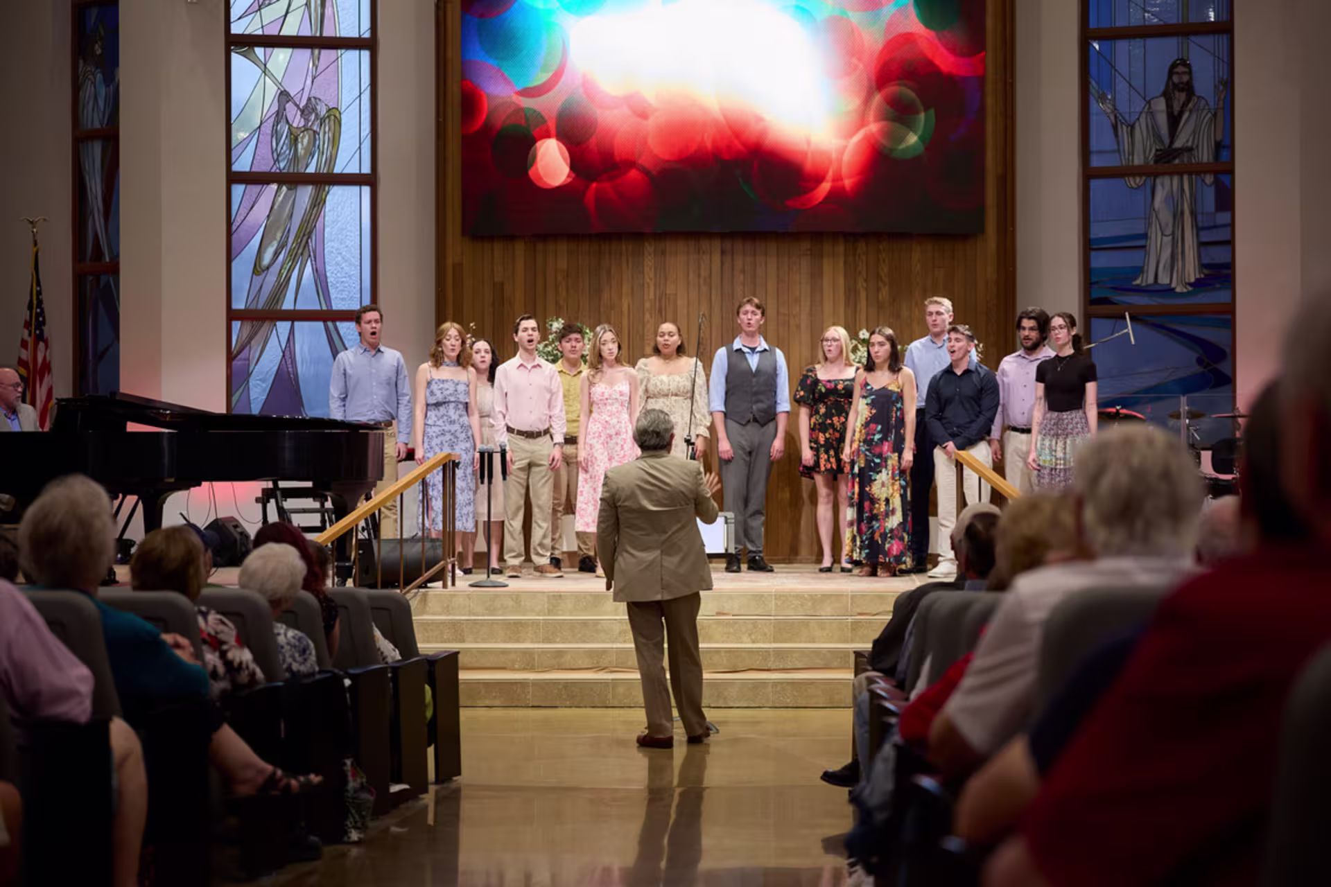 Church choir performing in a church while a conductor leads from the front.