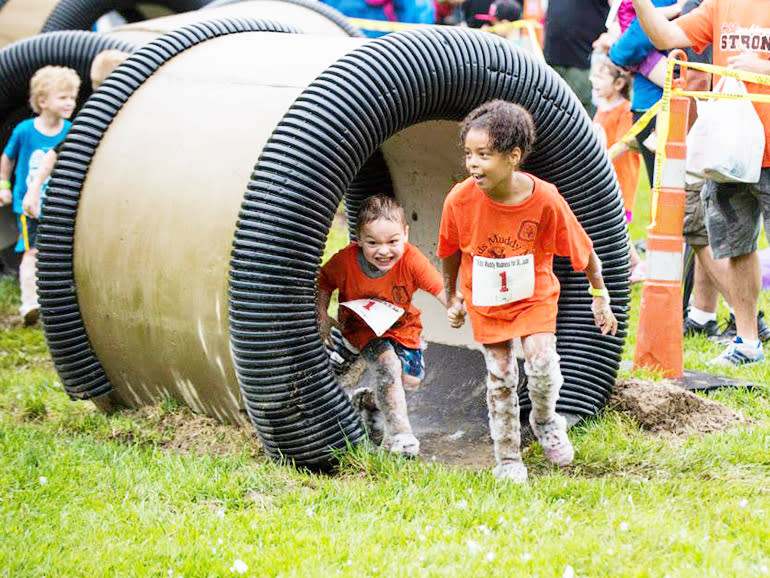 Two kids exiting a large tube